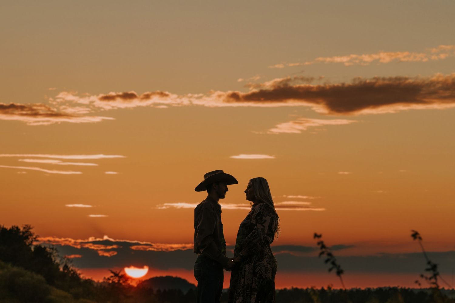 Dramatic orange sunset silhouettes figures against vibrant sky.