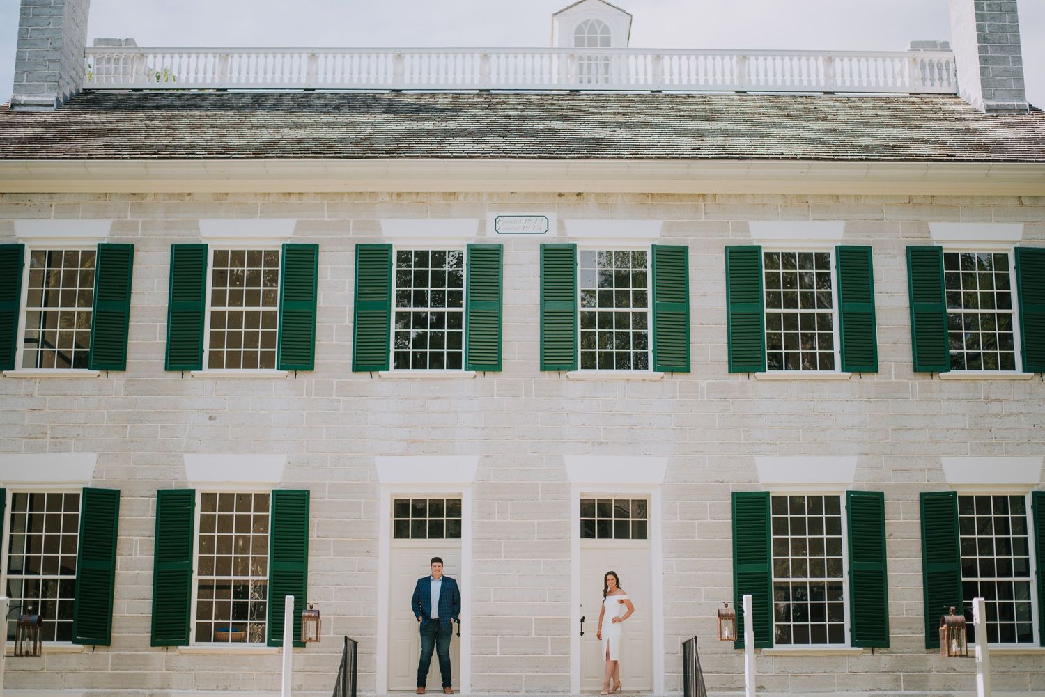Historic white colonial building with green shutters and multiple windows.
