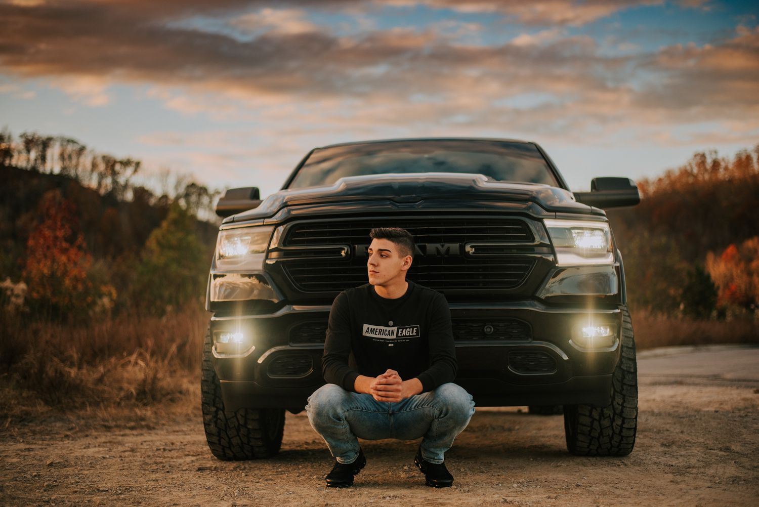 A black pickup truck with headlights on during golden hour.