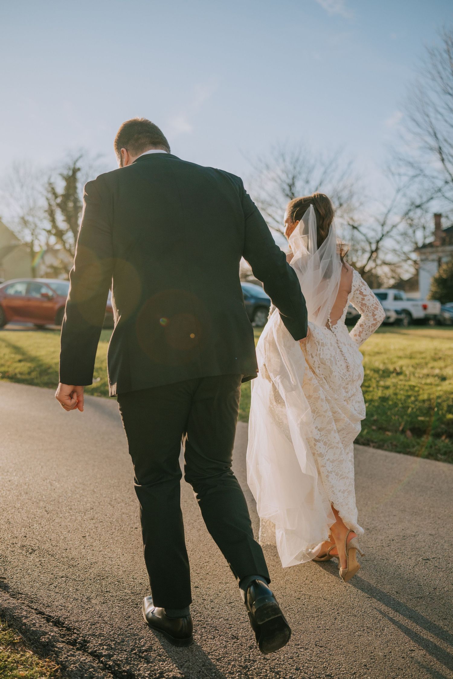 Newlyweds walking away together on path after wedding ceremony at sunset.