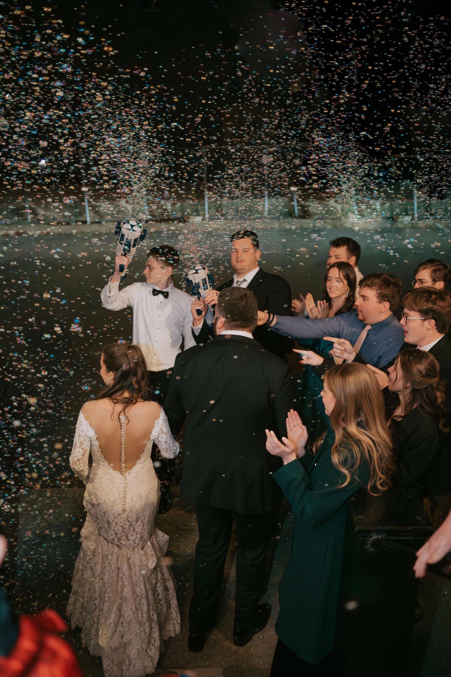 Wedding celebration with confetti falling over a crowd of guests dancing at an evening reception party.