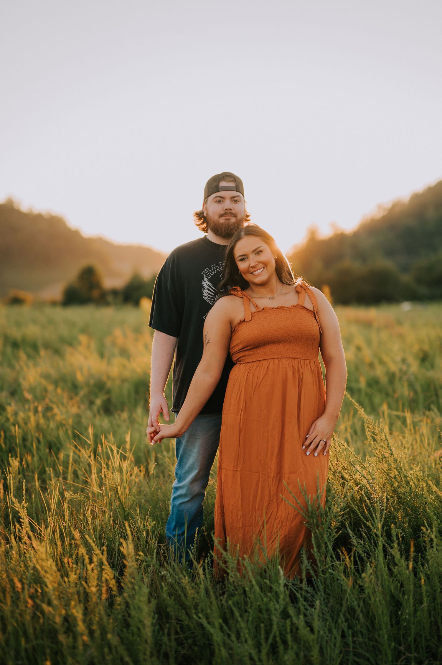 A couple shares intimate moments in a golden sunlit field of tall grass.