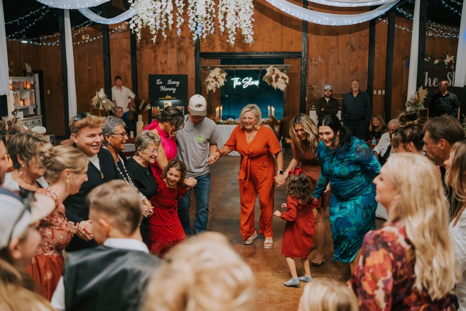 Wedding reception guests dancing and celebrating in a rustic wooden venue.