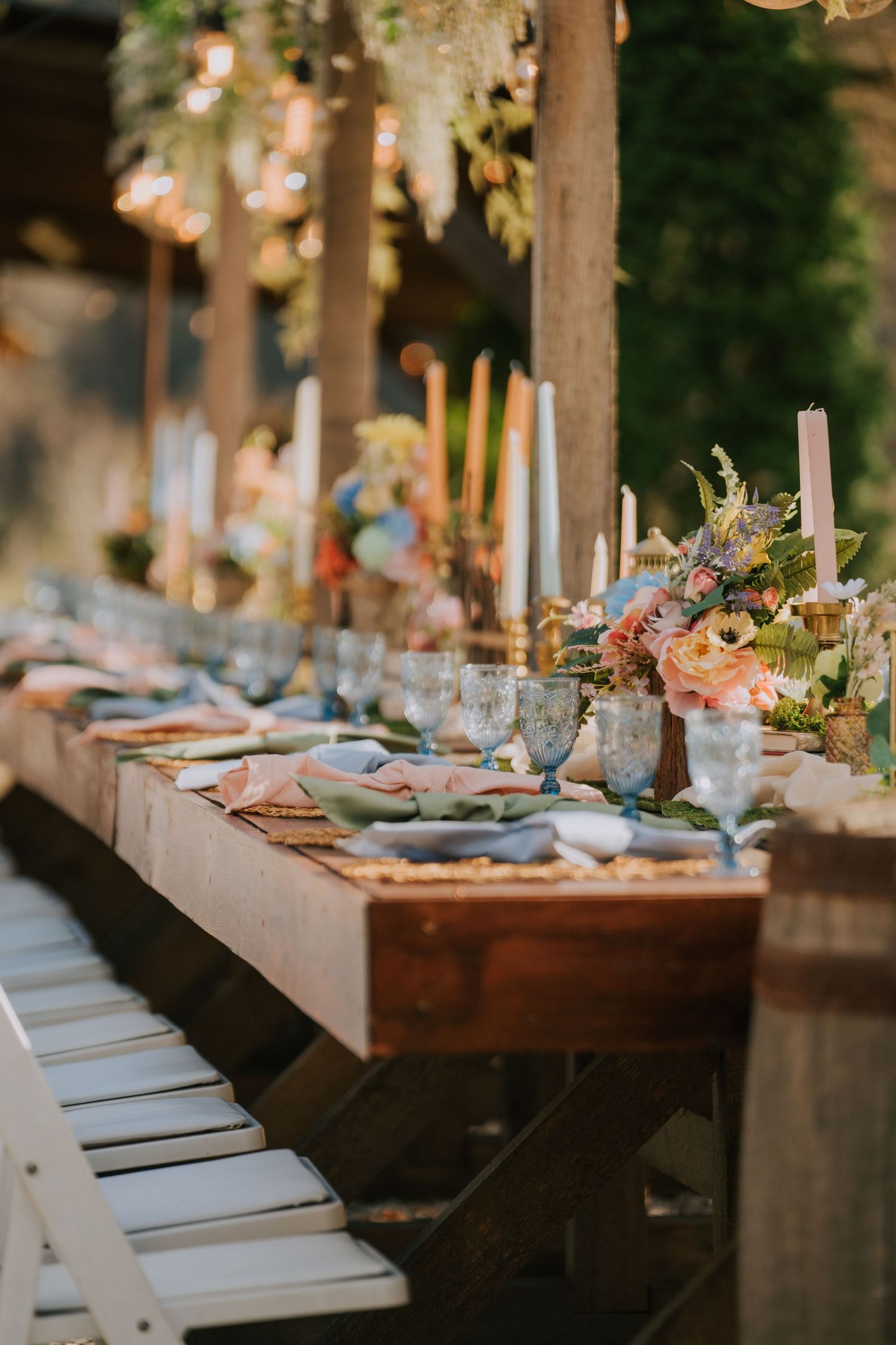 Long wooden reception table set with elegant place settings and floral decorations.