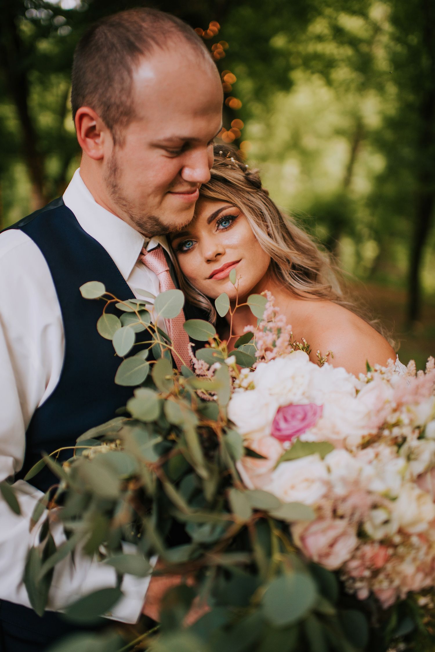 Intimate wedding portraits with soft pink florals and eucalyptus in natural lighting.