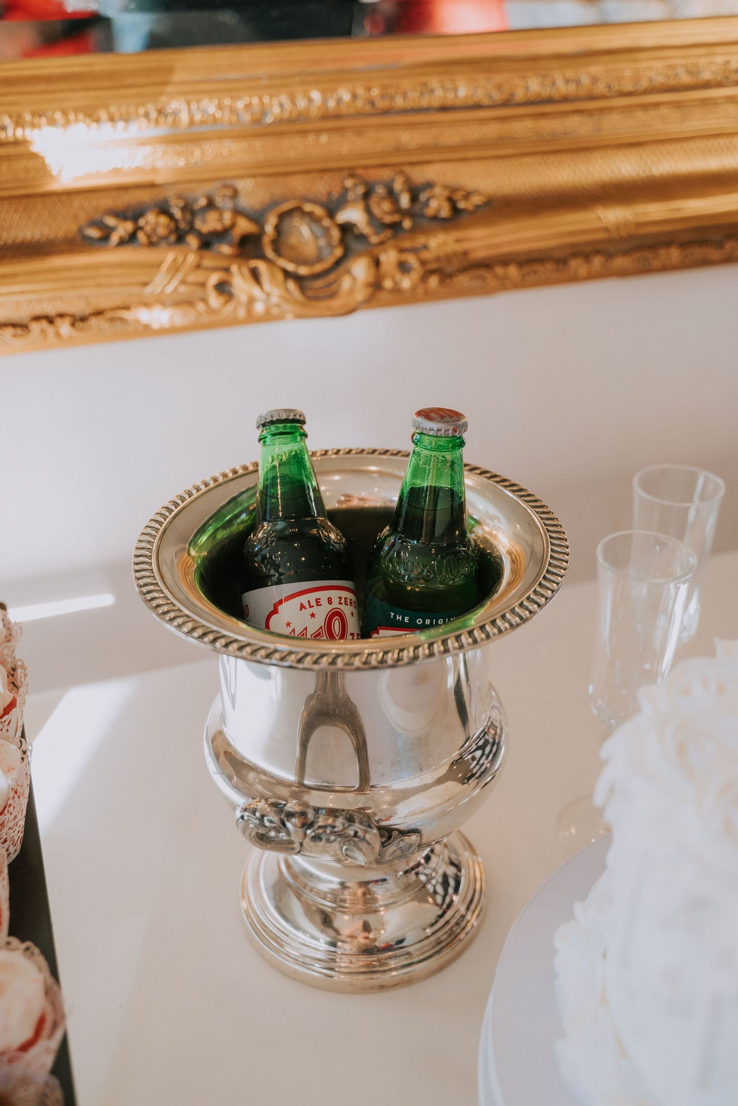 Green glass bottles chilling in an elegant silver champagne bucket with ornate details.