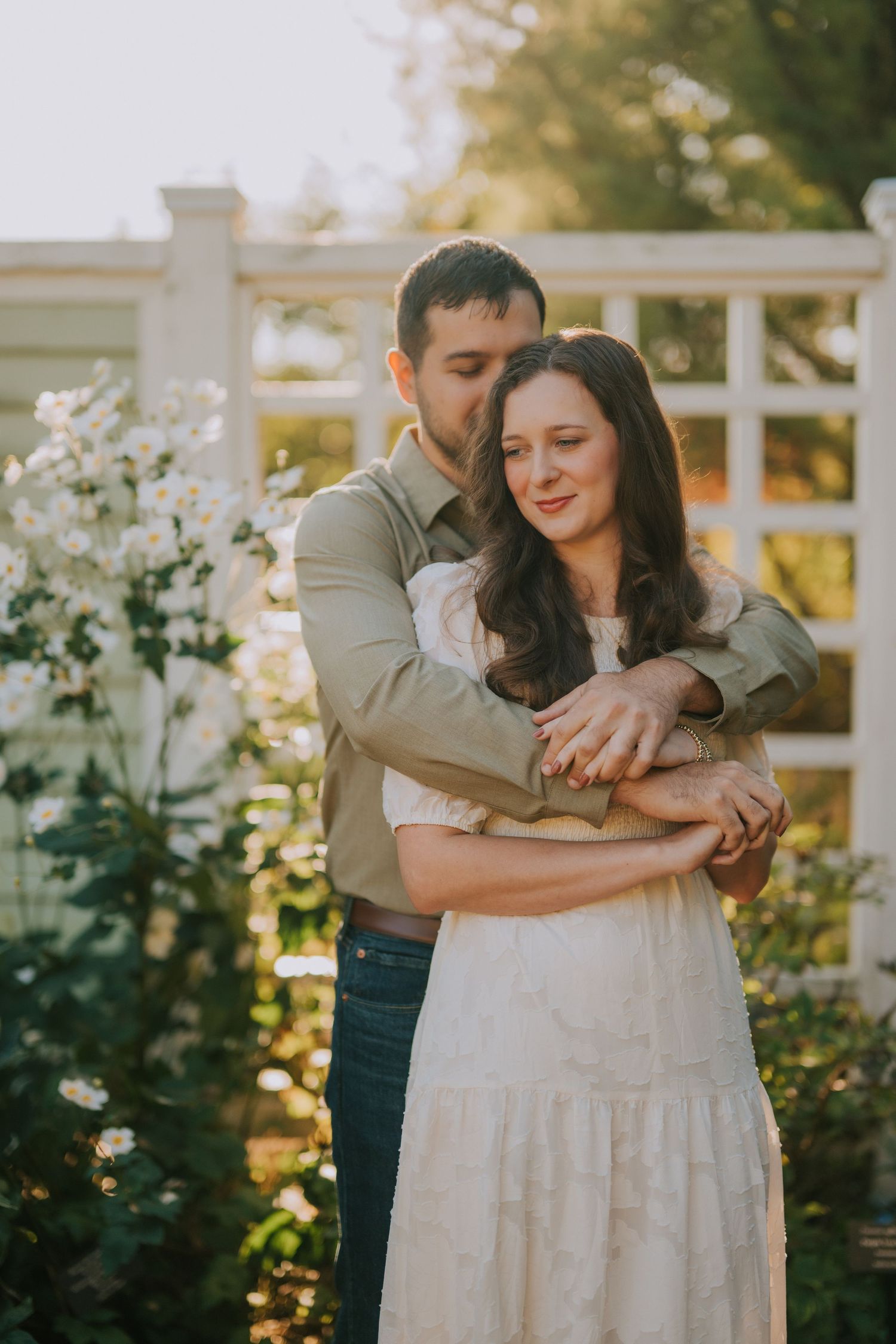 Sweet candid moment captured in a garden setting with white floral backdrop.