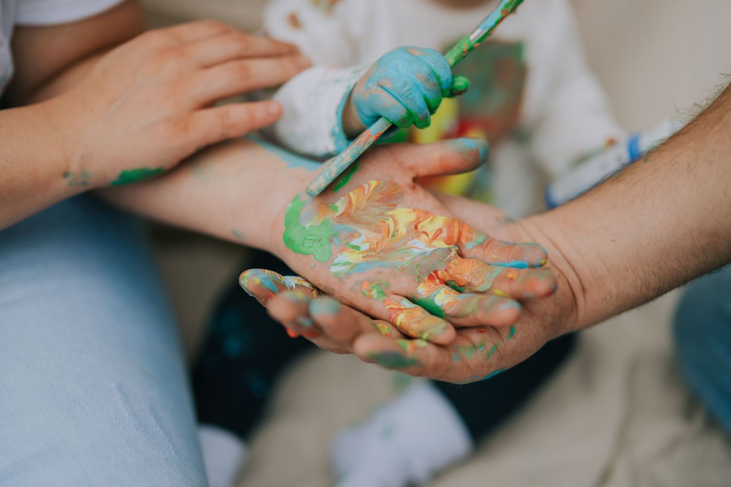 Close-up of hands painted with colorful paint creating artistic impressions.