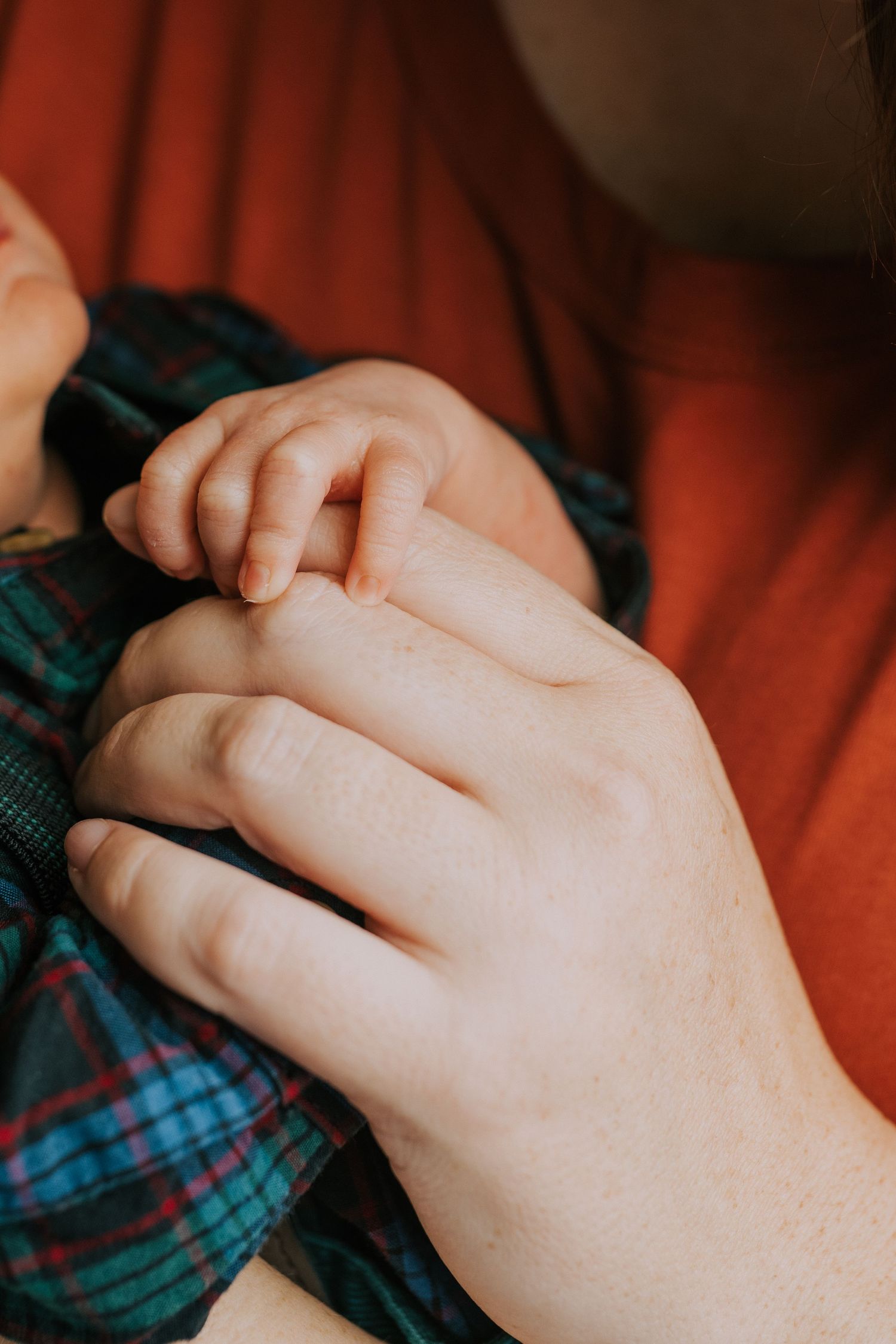 Close-up shot of clasped hands resting on plaid fabric.