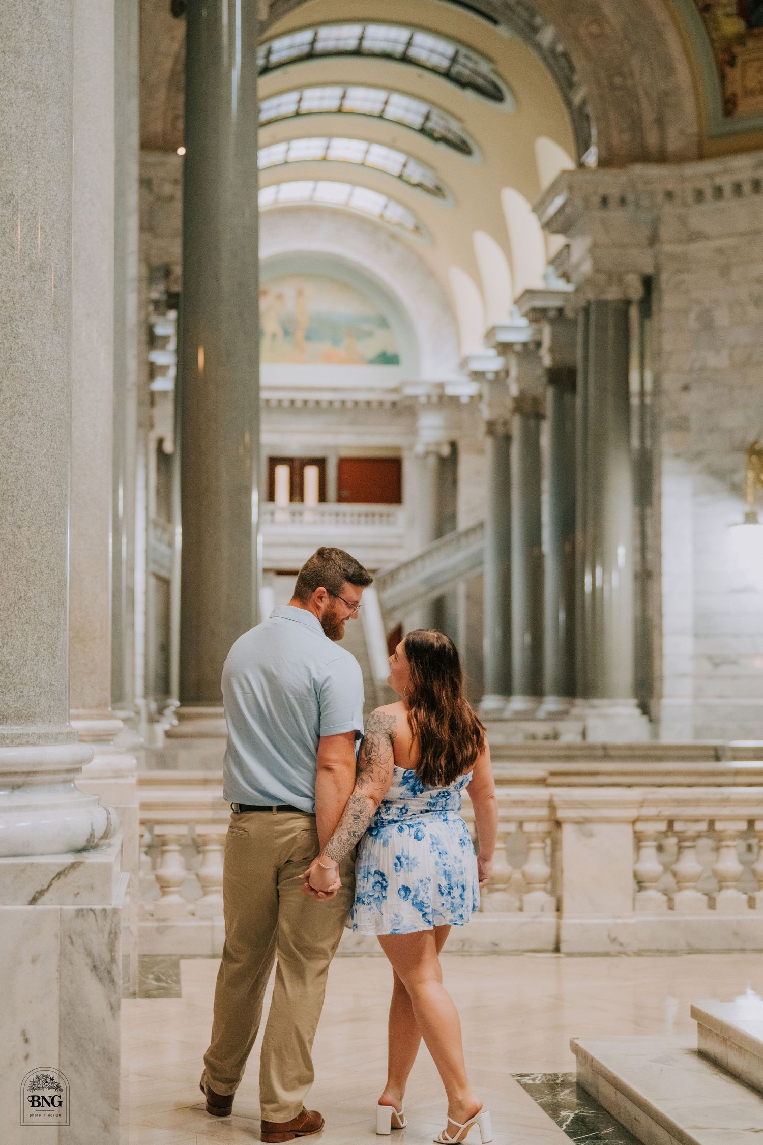 Couple dancing in an elegant marble hallway with classical columns and architectural details.