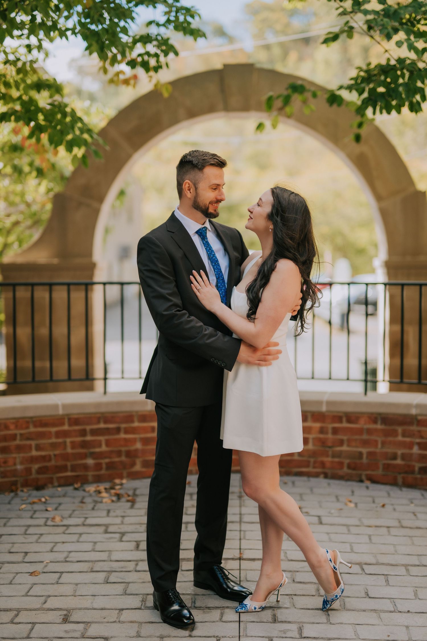Couple dancing and posing playfully under stone archways with blue heels.