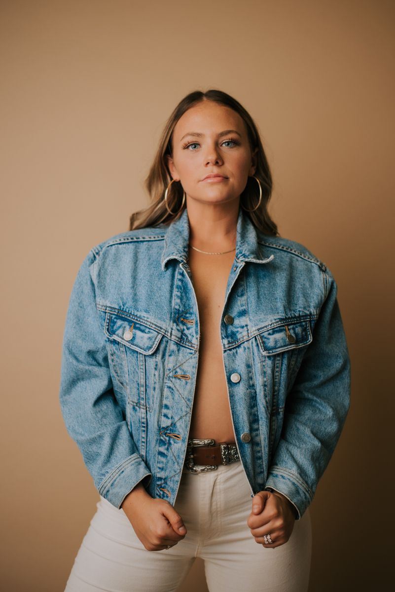 Fashion portraits featuring casual denim jacket and neutral tones against warm backdrop.