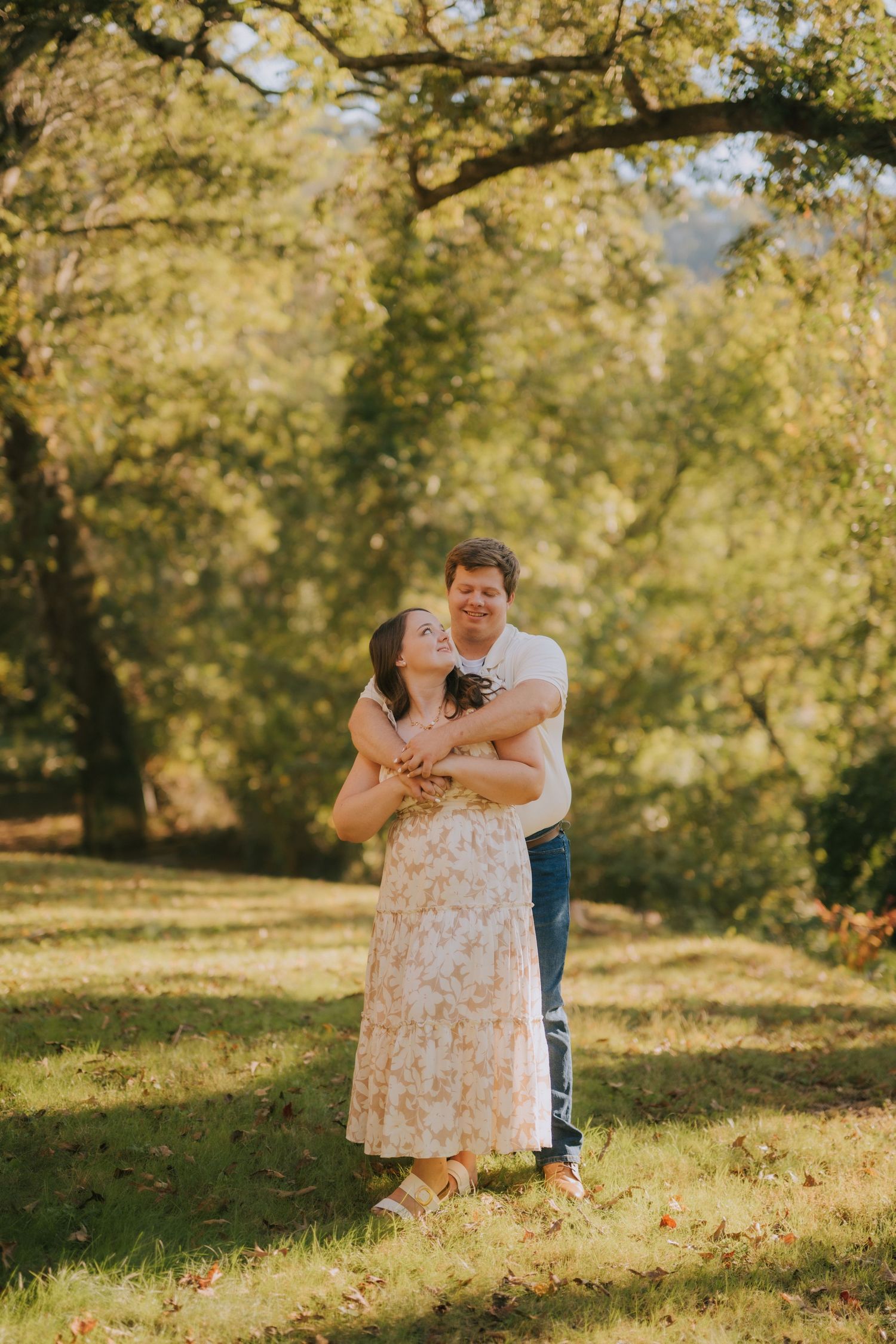 A romantic couple's portrait session in a sunlit park with autumn foliage.