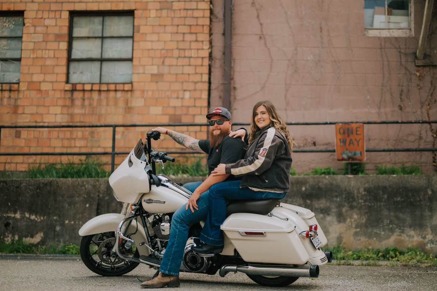 A white motorcycle parked against a brick building backdrop.
