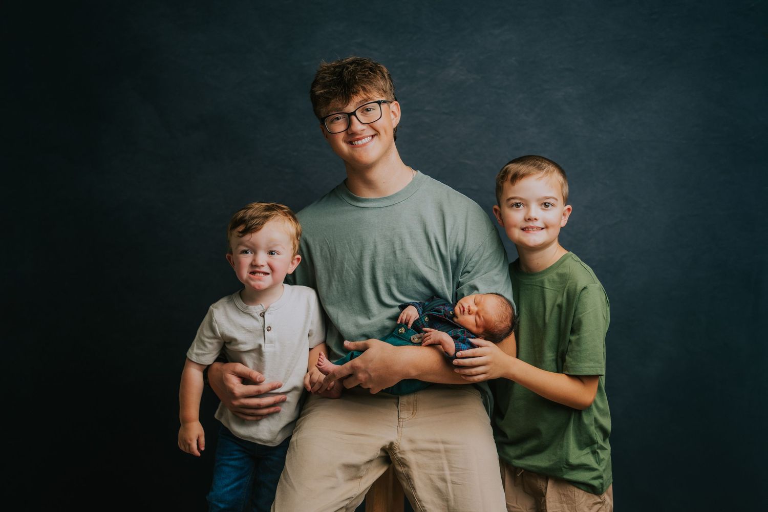 Modern family group photo with coordinated outfits against dark backdrop.