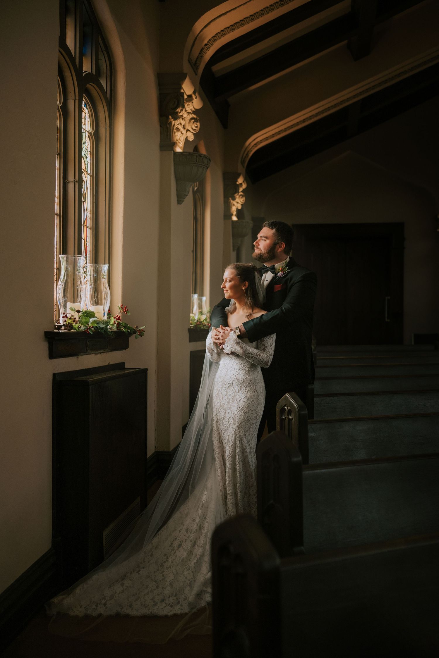 Romantic wedding photos taken in dimly lit church sanctuary with dramatic lighting.