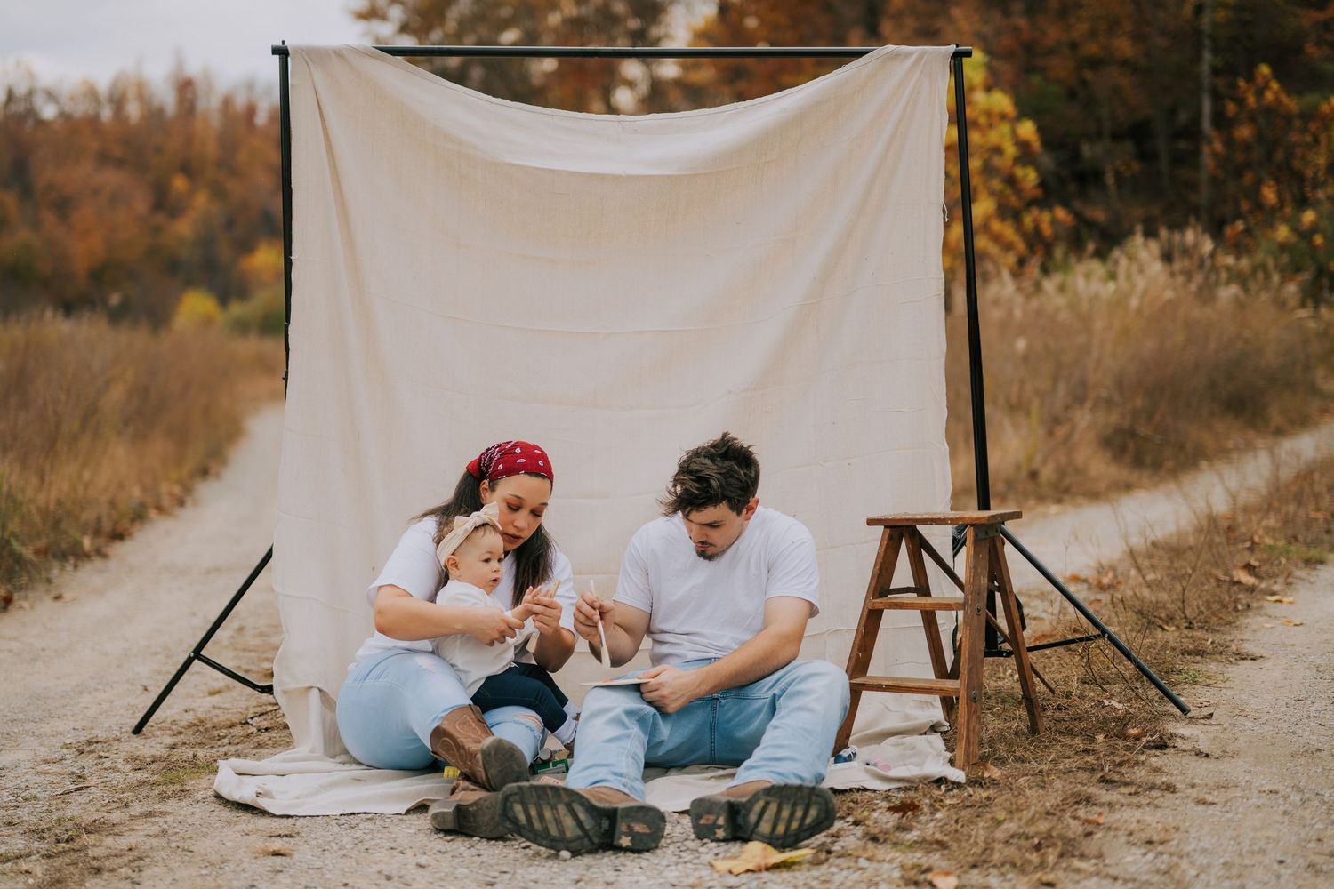 Outdoor photo session setup with white backdrop against autumn foliage.