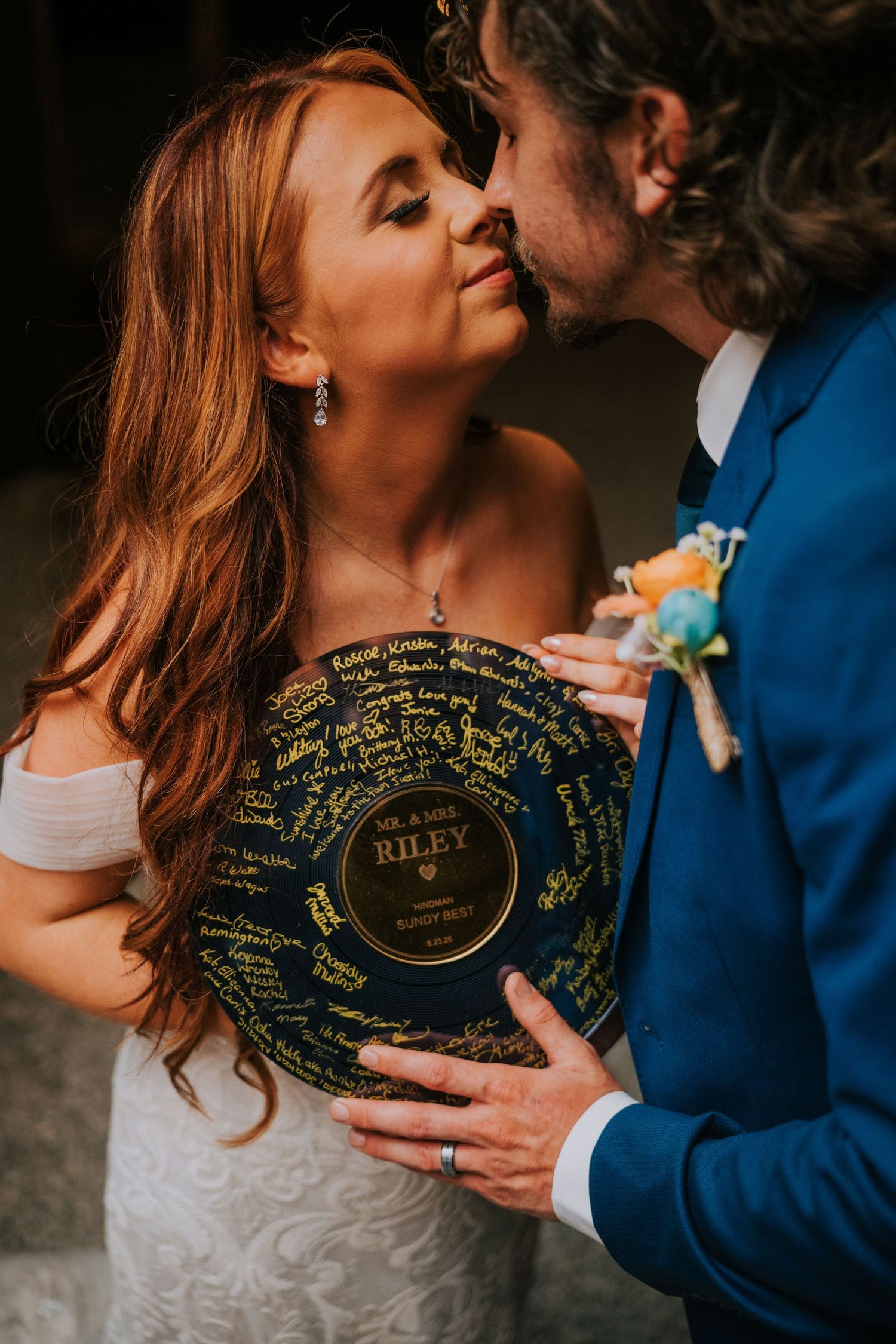 Couple holds vinyl record with signatures and messages at wedding reception.