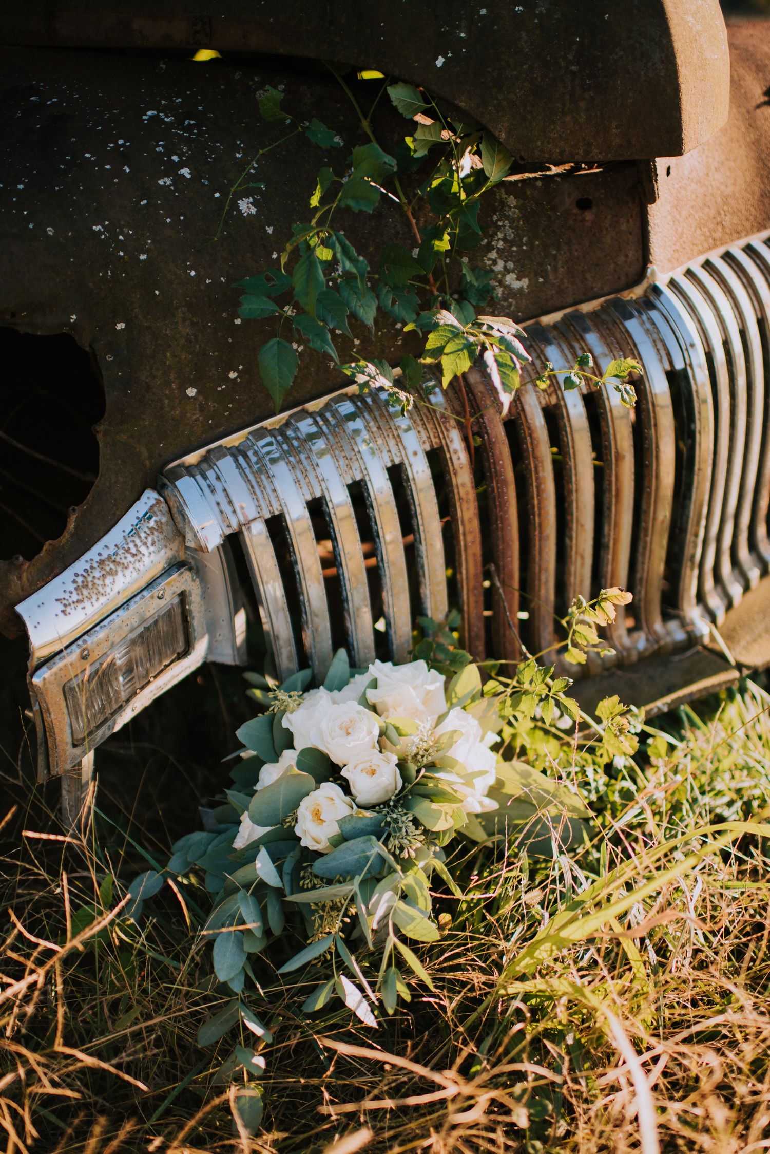 White flowers bloom against a rustic metal radiator in a vintage-style garden setting.