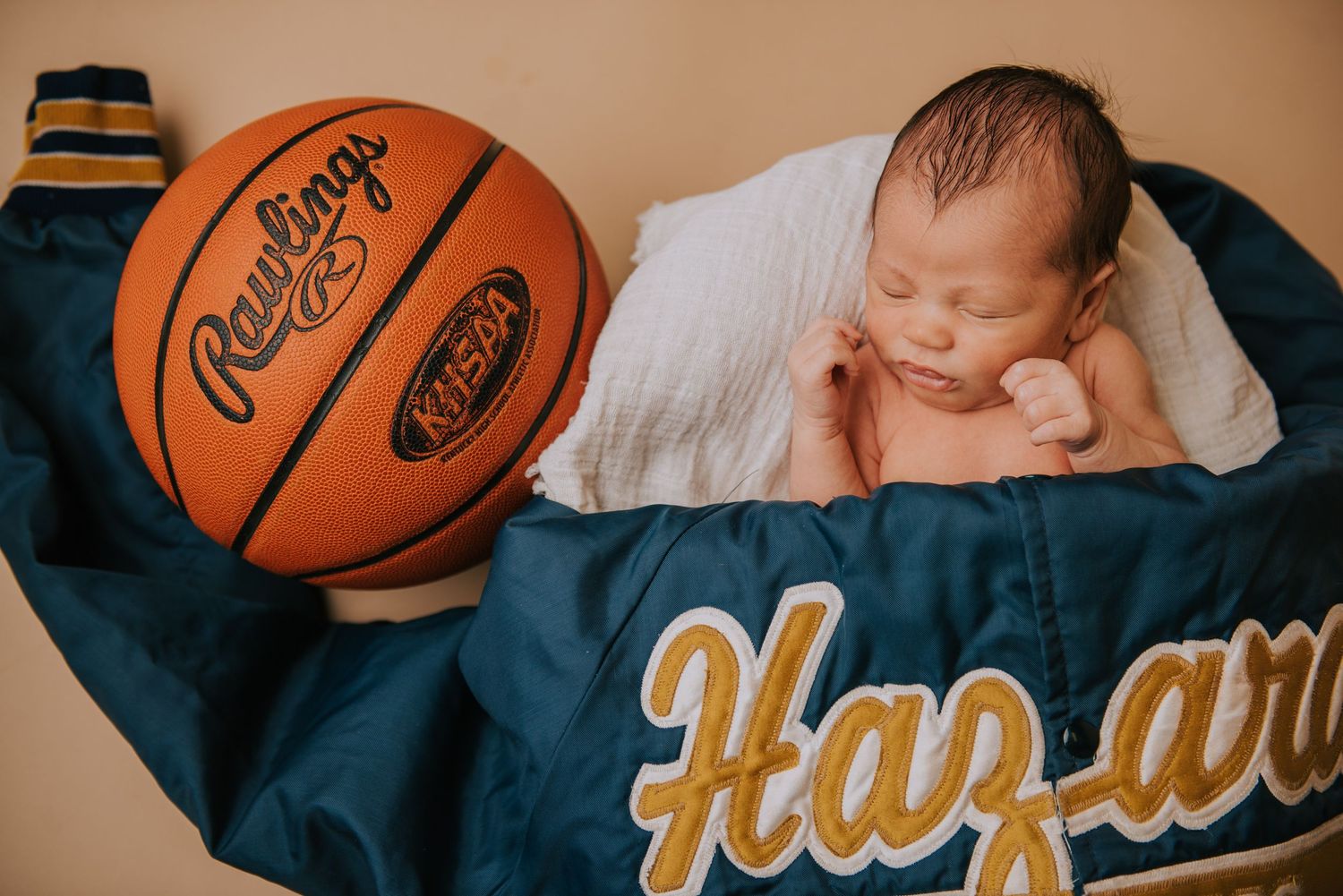 Newborn photography setup with basketball and blue blanket.