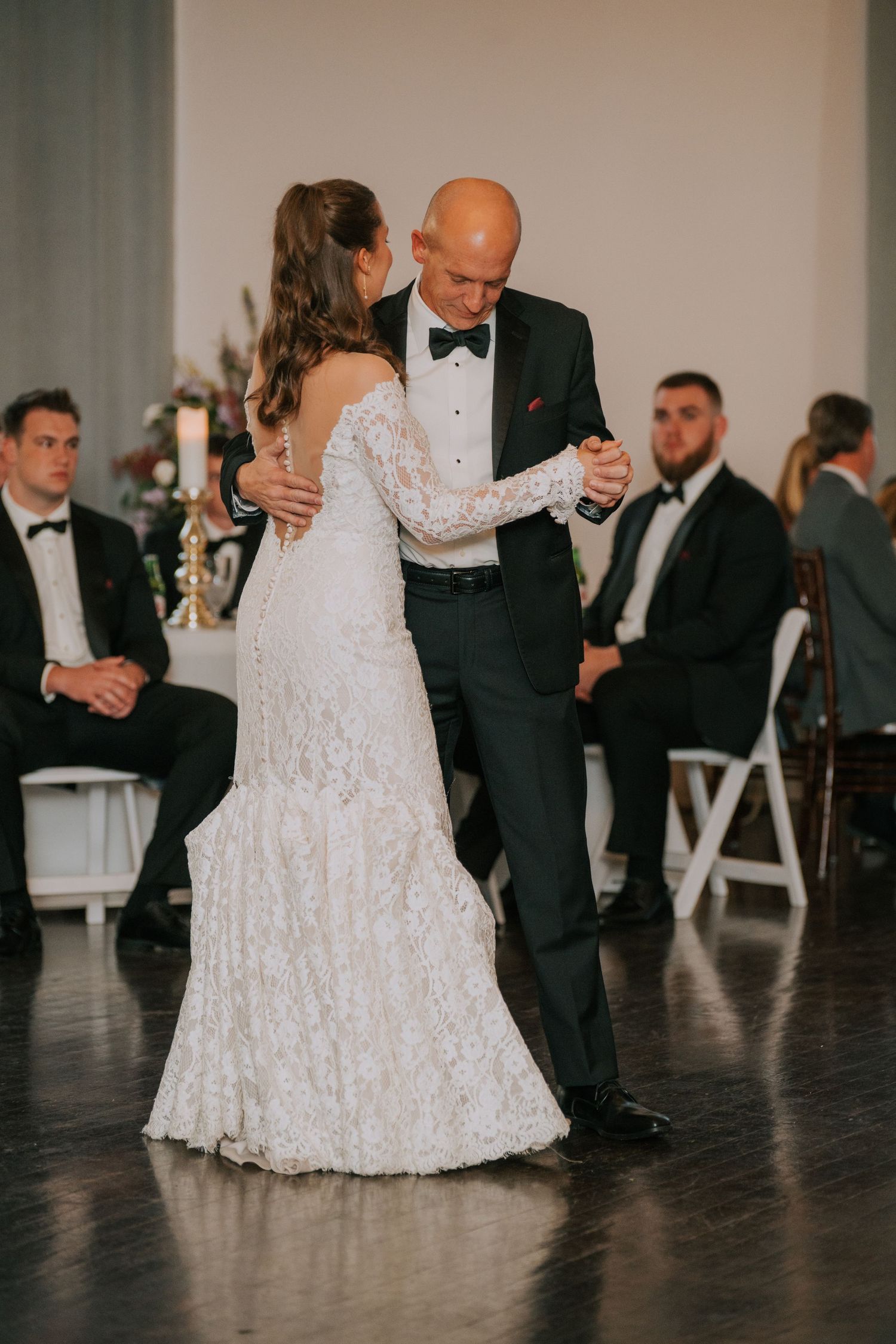A tender dance moment between two people in formal attire at an elegant wedding reception.