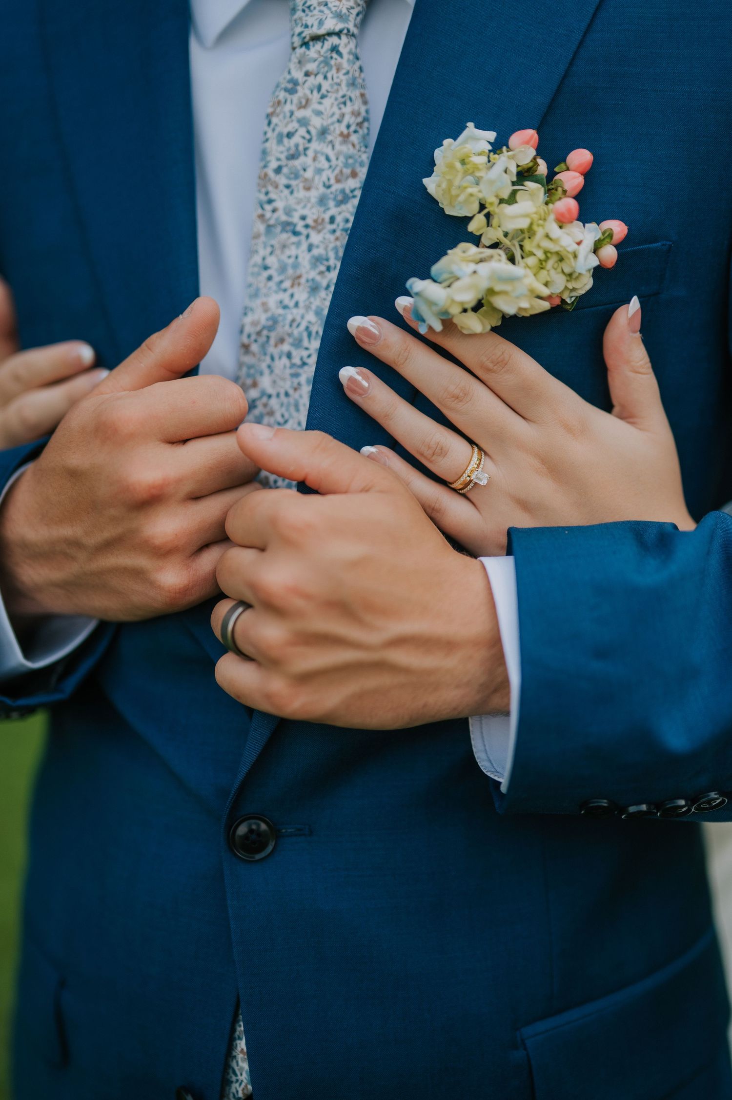 Close-up shots of hands holding a delicate floral bouquet against a navy blue suit.