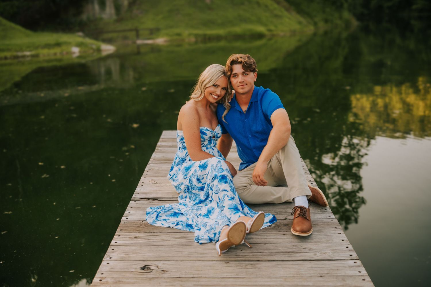 Couple relaxes together on wooden dock overlooking serene lake.