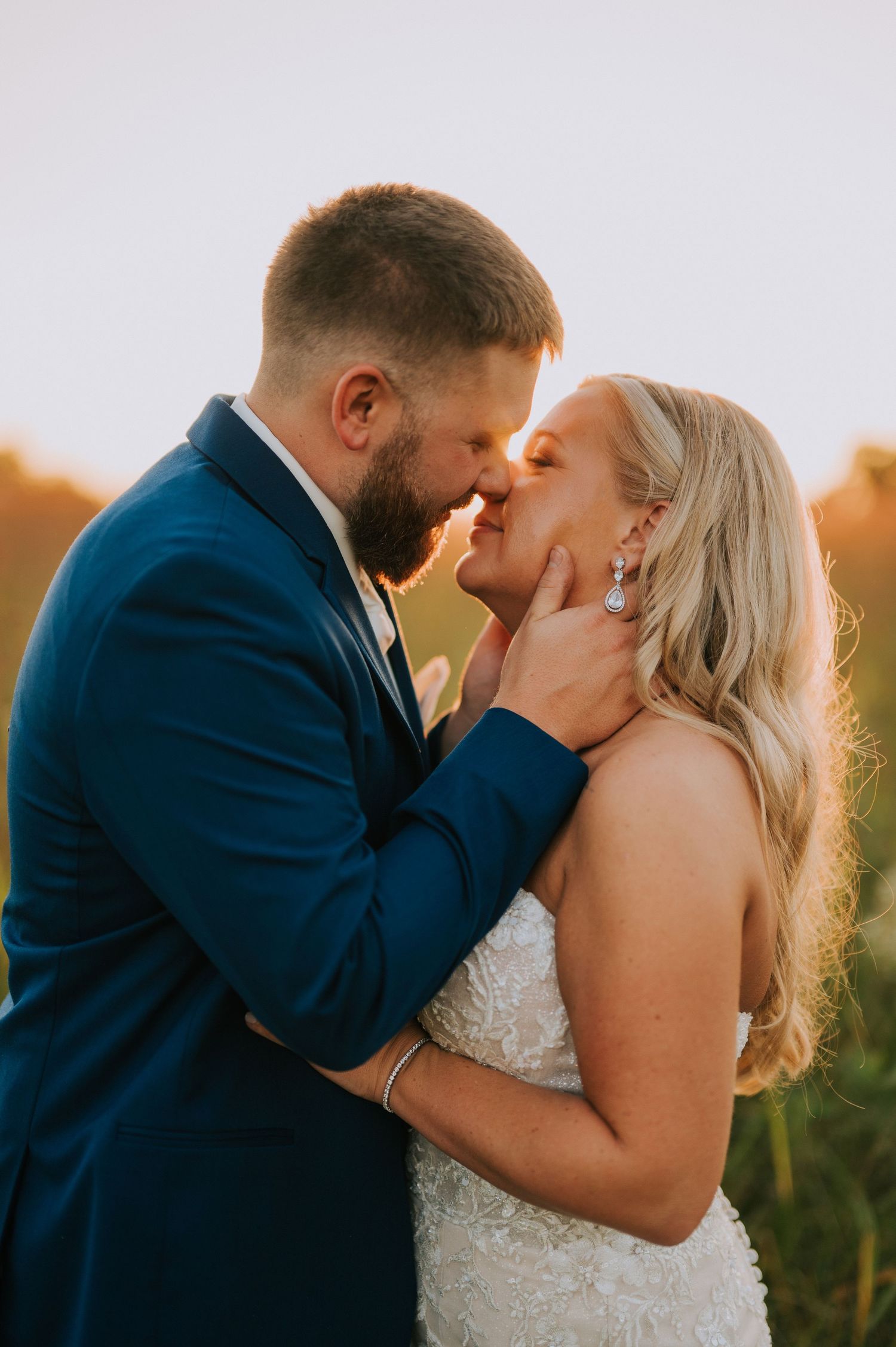 A romantic sunset kiss between newlyweds with golden light illuminating the scene.