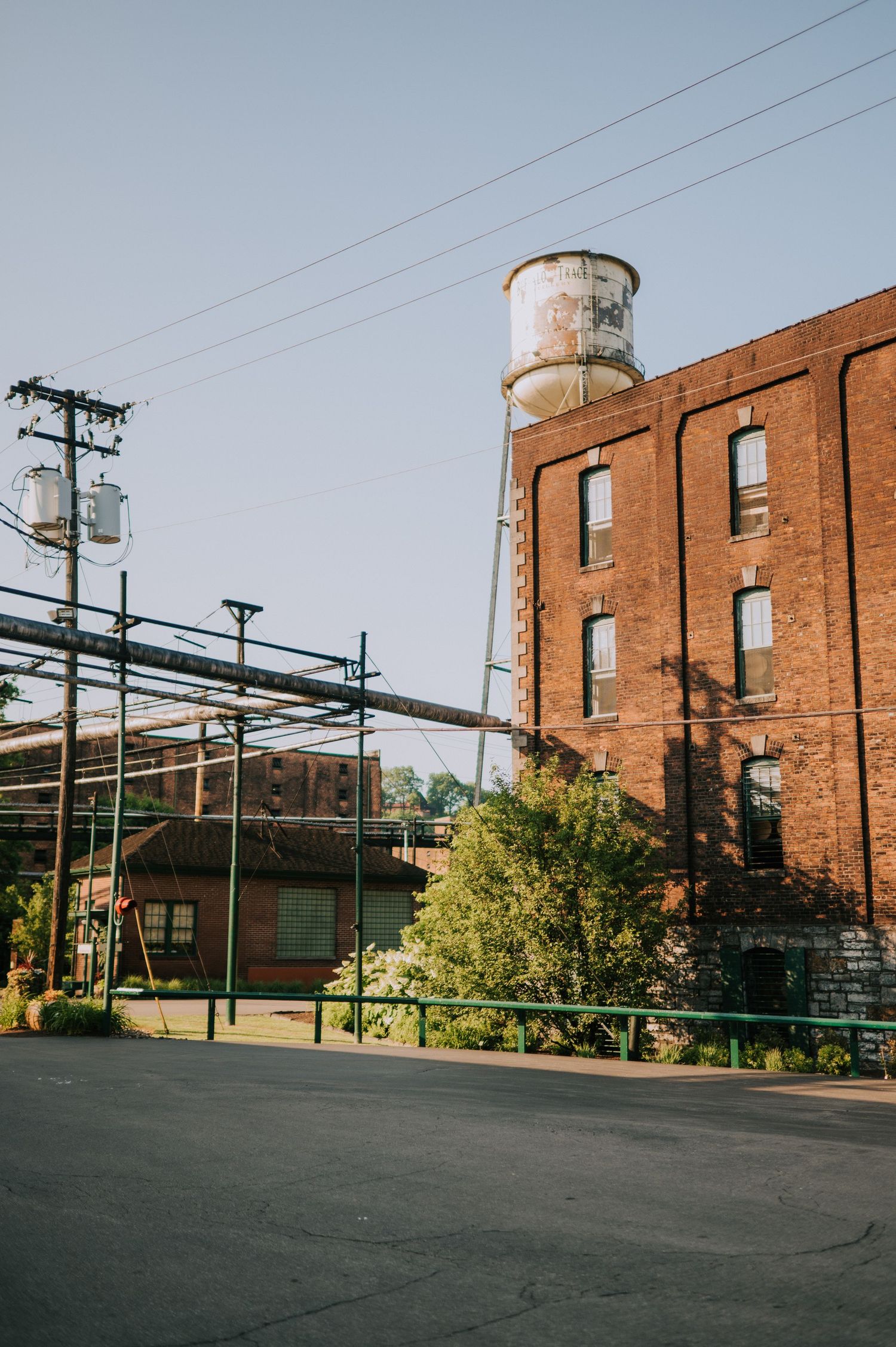 Industrial complex exterior featuring red brick buildings and water towers under clear skies.