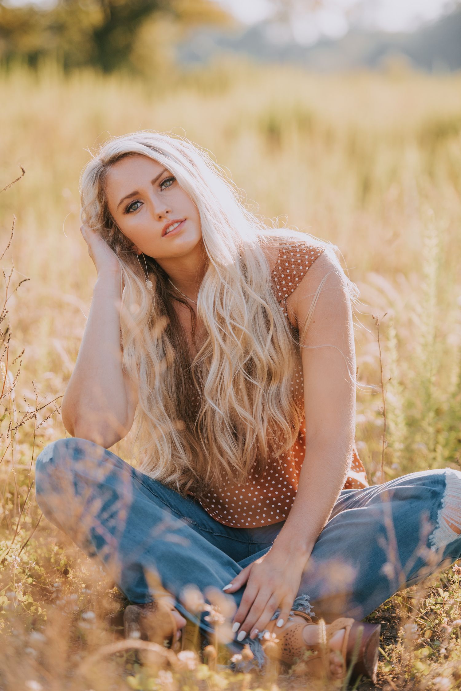 A dreamy portrait in a golden wheat field wearing a polka dot top and jeans.