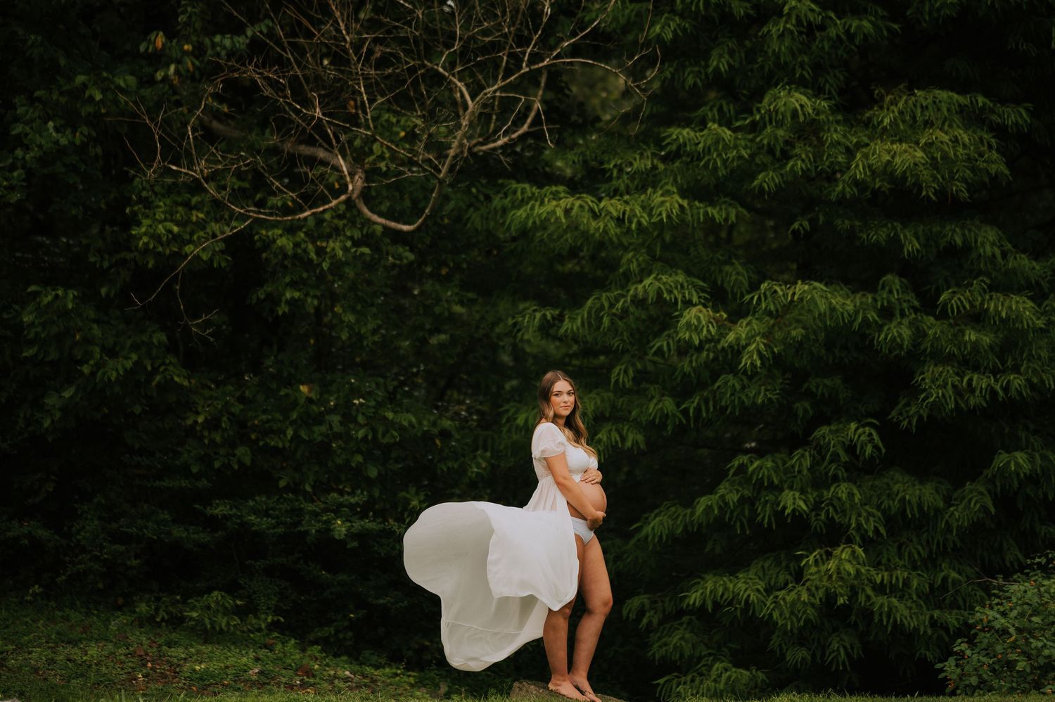 A flowing white dress catches the breeze in a garden setting.
