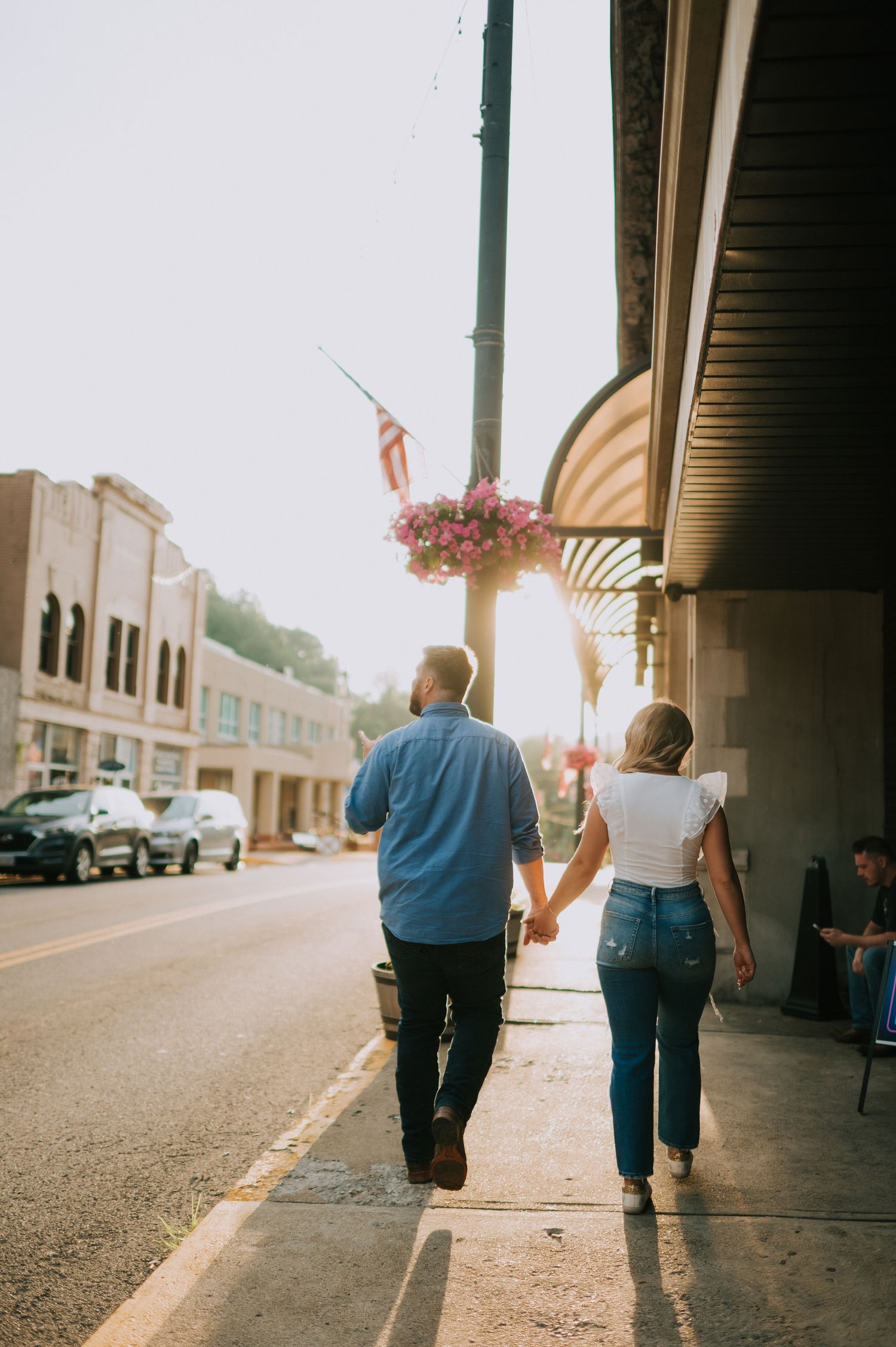 A couple walks together under an awning in a small town setting.