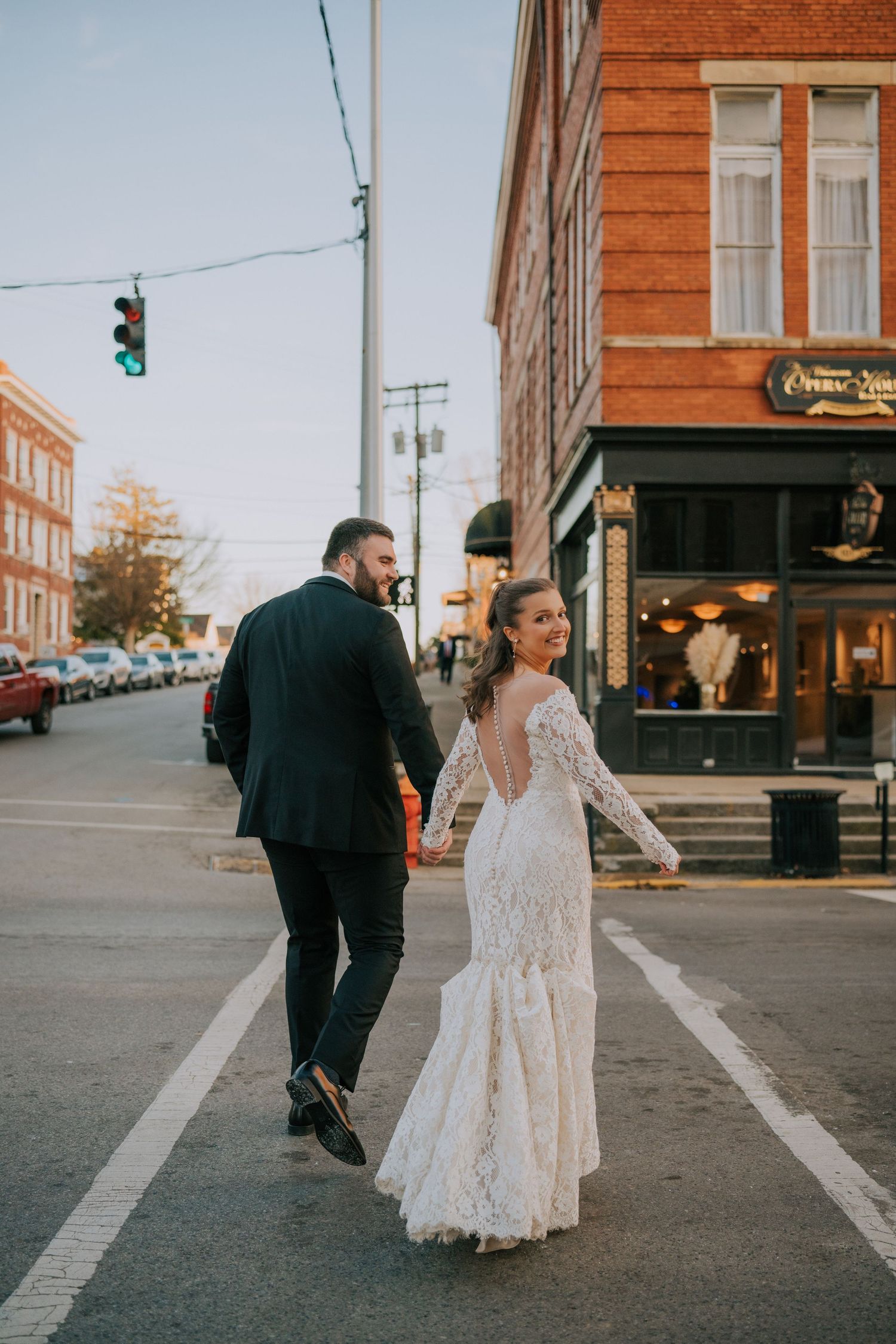 A couple walking down a charming urban street lined with vintage brick buildings during their wedding celebration.