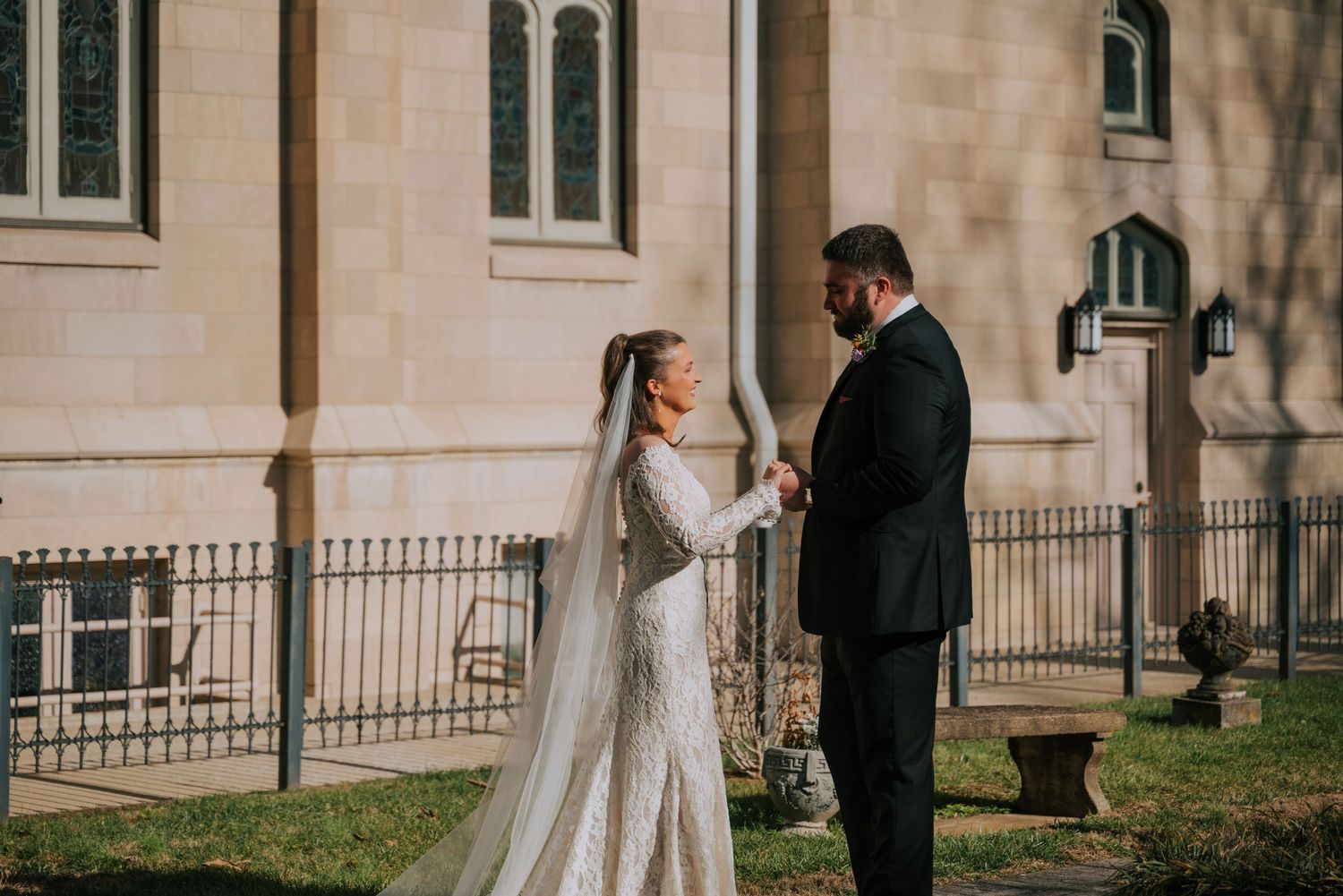 A couple shares a tender moment in front of a historic church on their wedding day, surrounded by stone architecture.