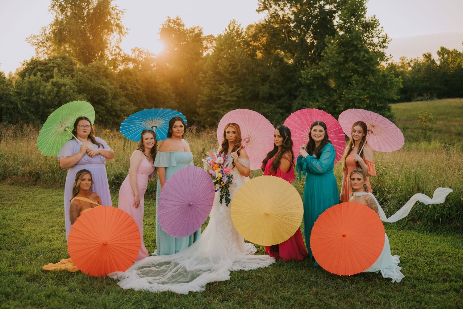 Colorful circular umbrellas create a whimsical outdoor photo session at sunset in a grassy field.