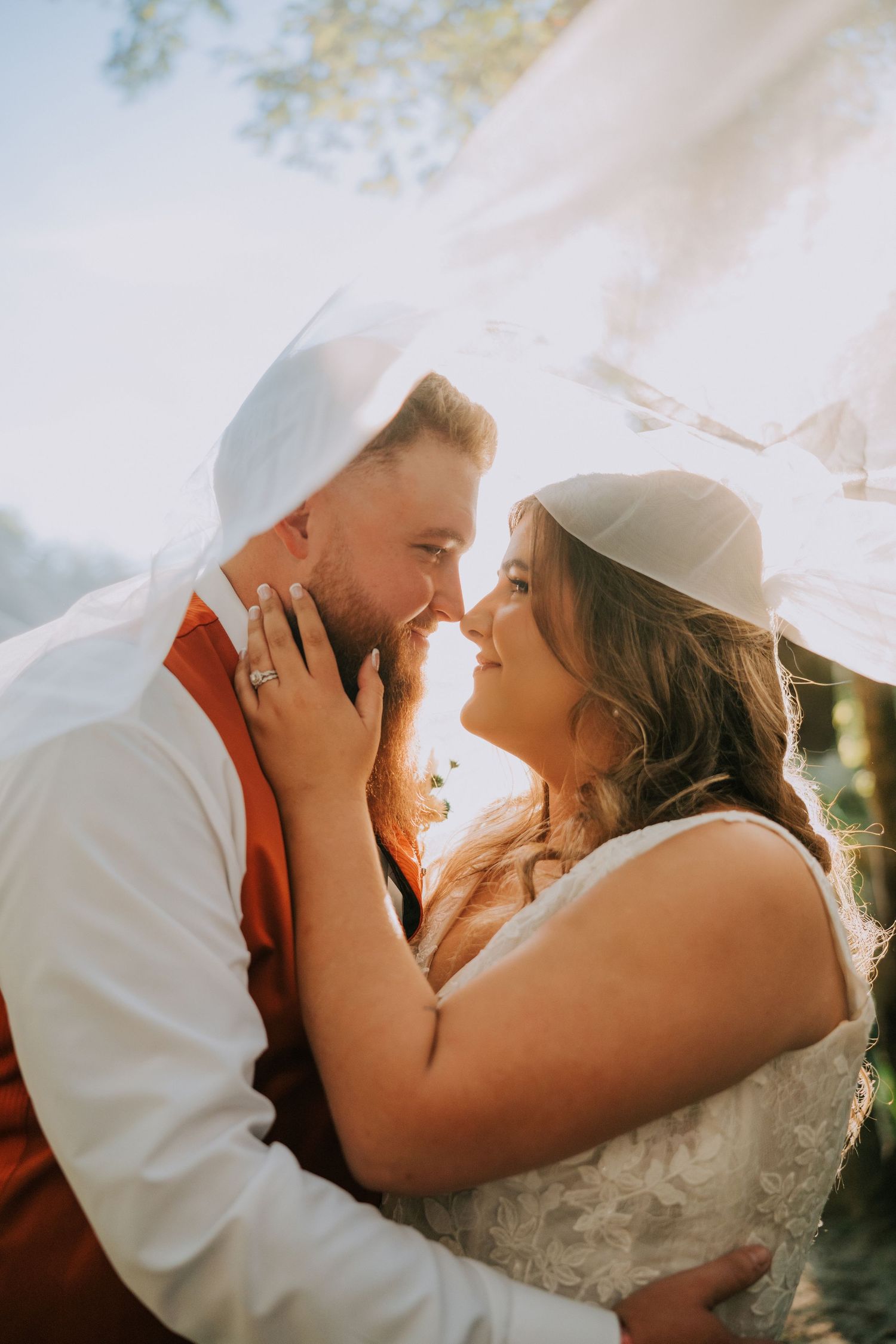 Romantic wedding couple sharing intimate kisses in golden sunlight during outdoor photo session.
