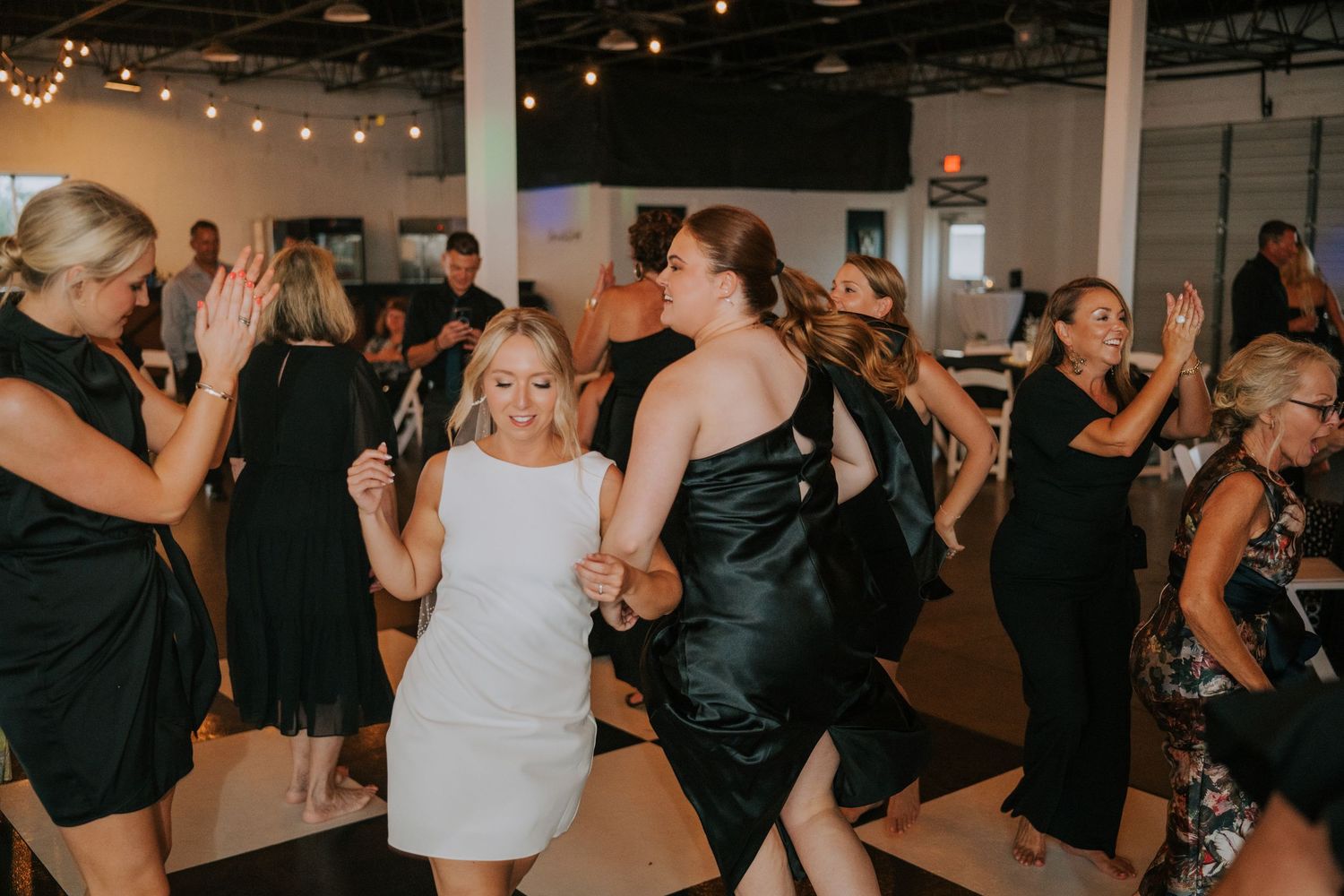 Wedding guests dancing and celebrating on a dimly lit dance floor.