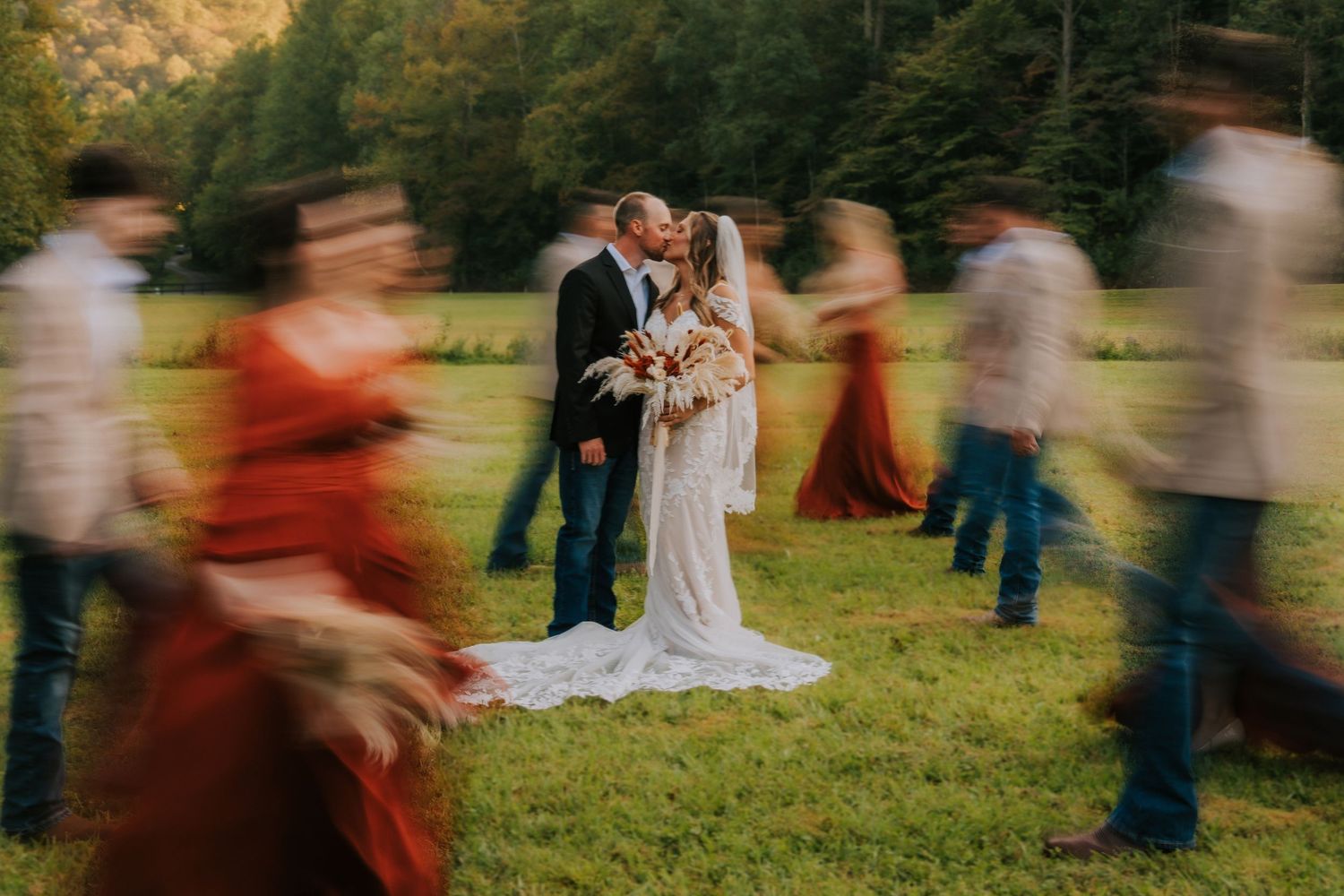 Motion-blurred wedding celebration with guests dancing outdoors.