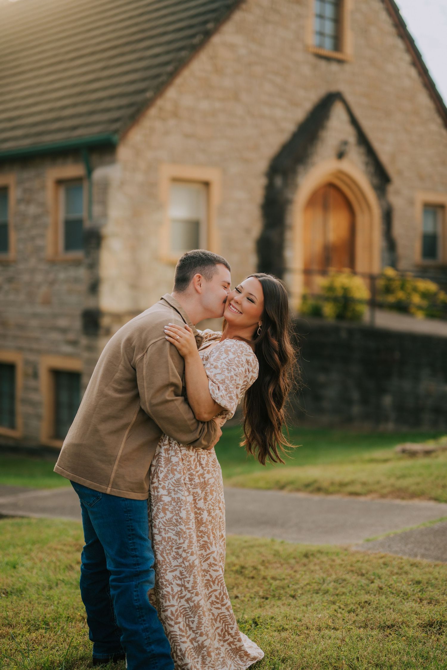 A romantic scene unfolds on a grassy lawn in front of a stone cottage.