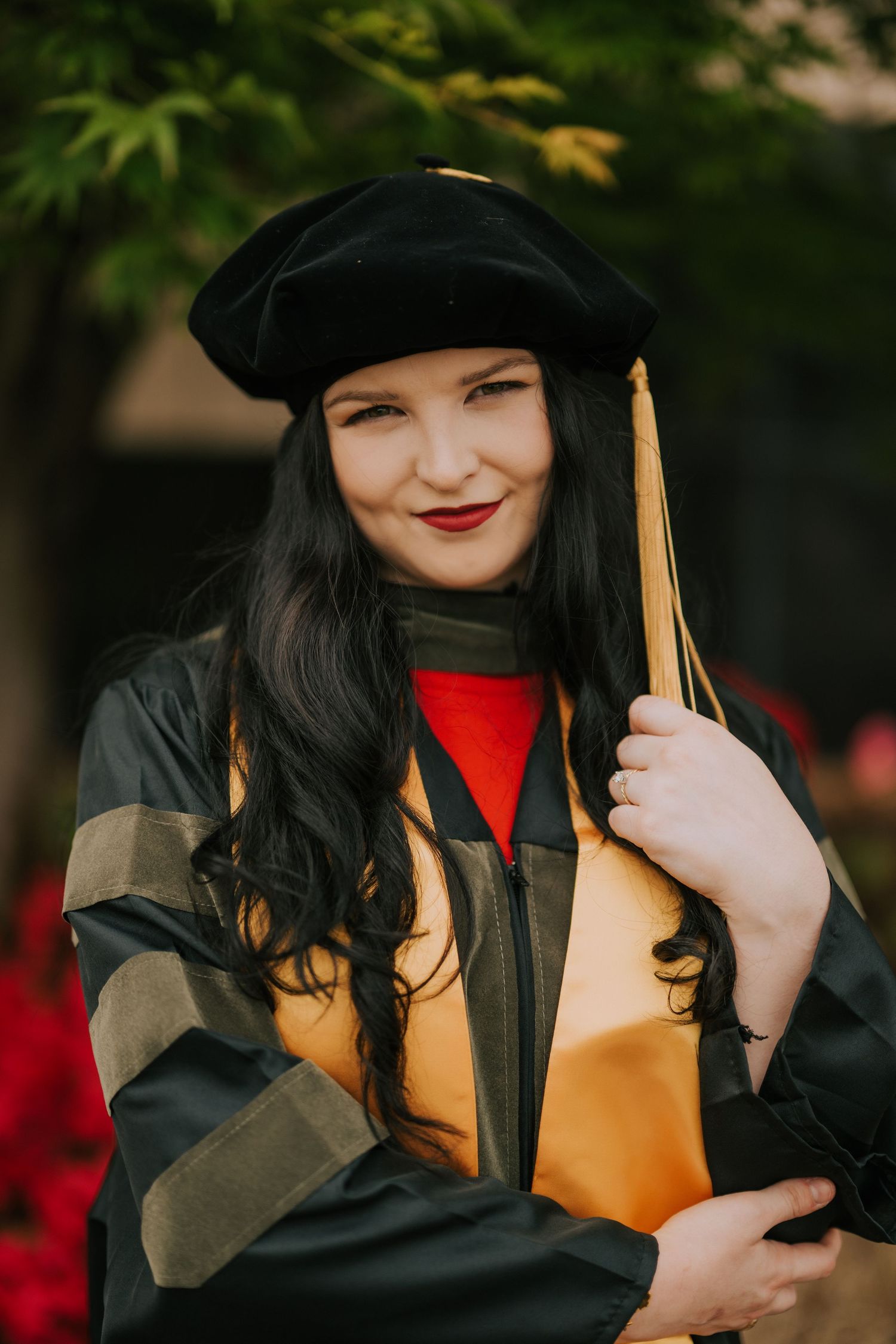 Graduate in black cap and gown smiling joyfully with yellow tassel.