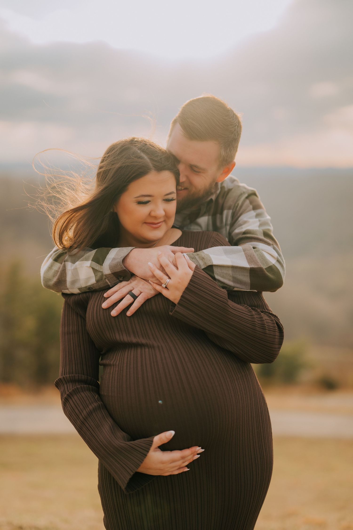 A maternity photoshoot captures tender moments between expectant parents in warm autumn light.