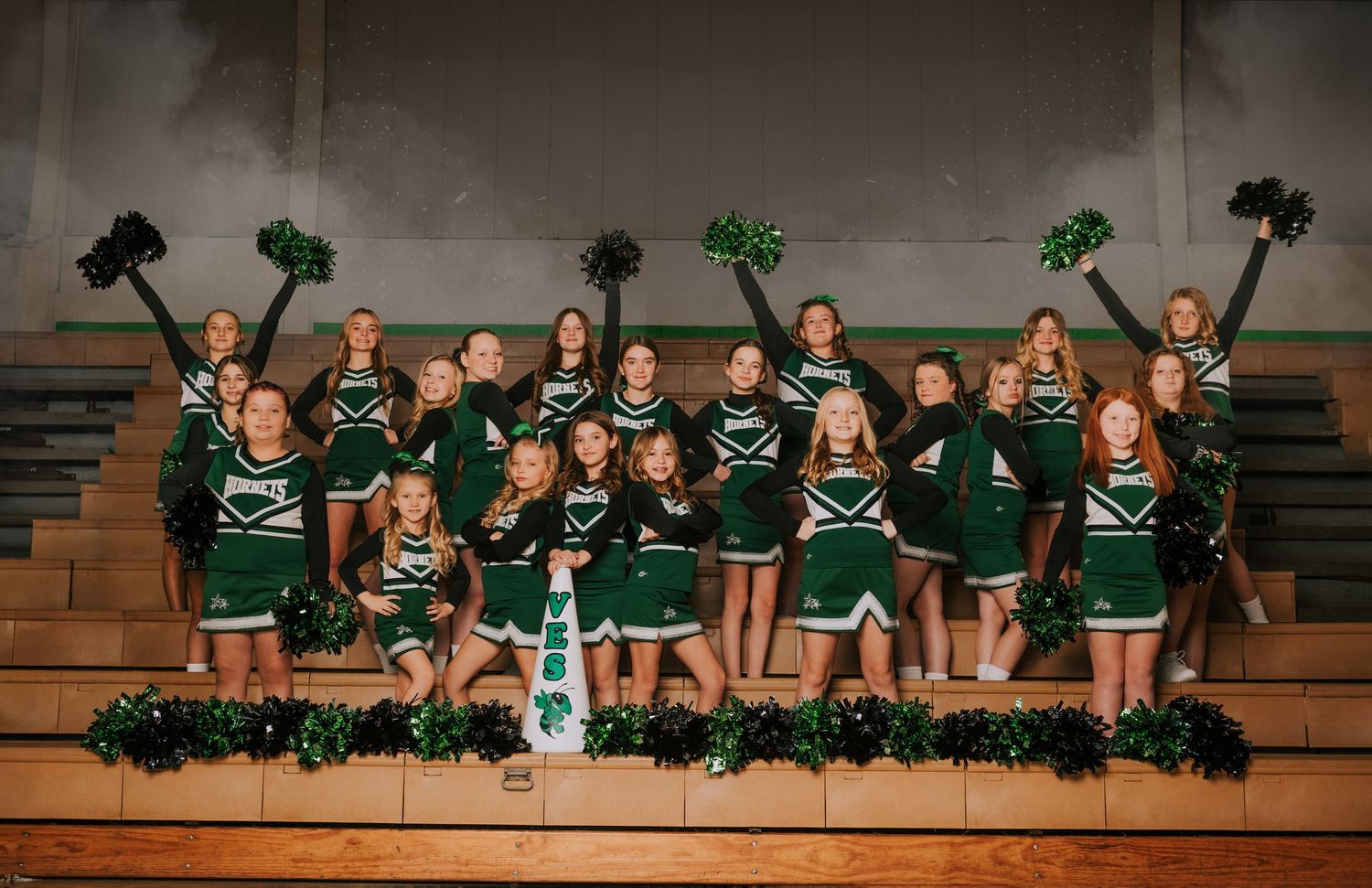 A panoramic sequence shows cheerleaders in green uniforms performing a synchronized routine on wooden bleachers.