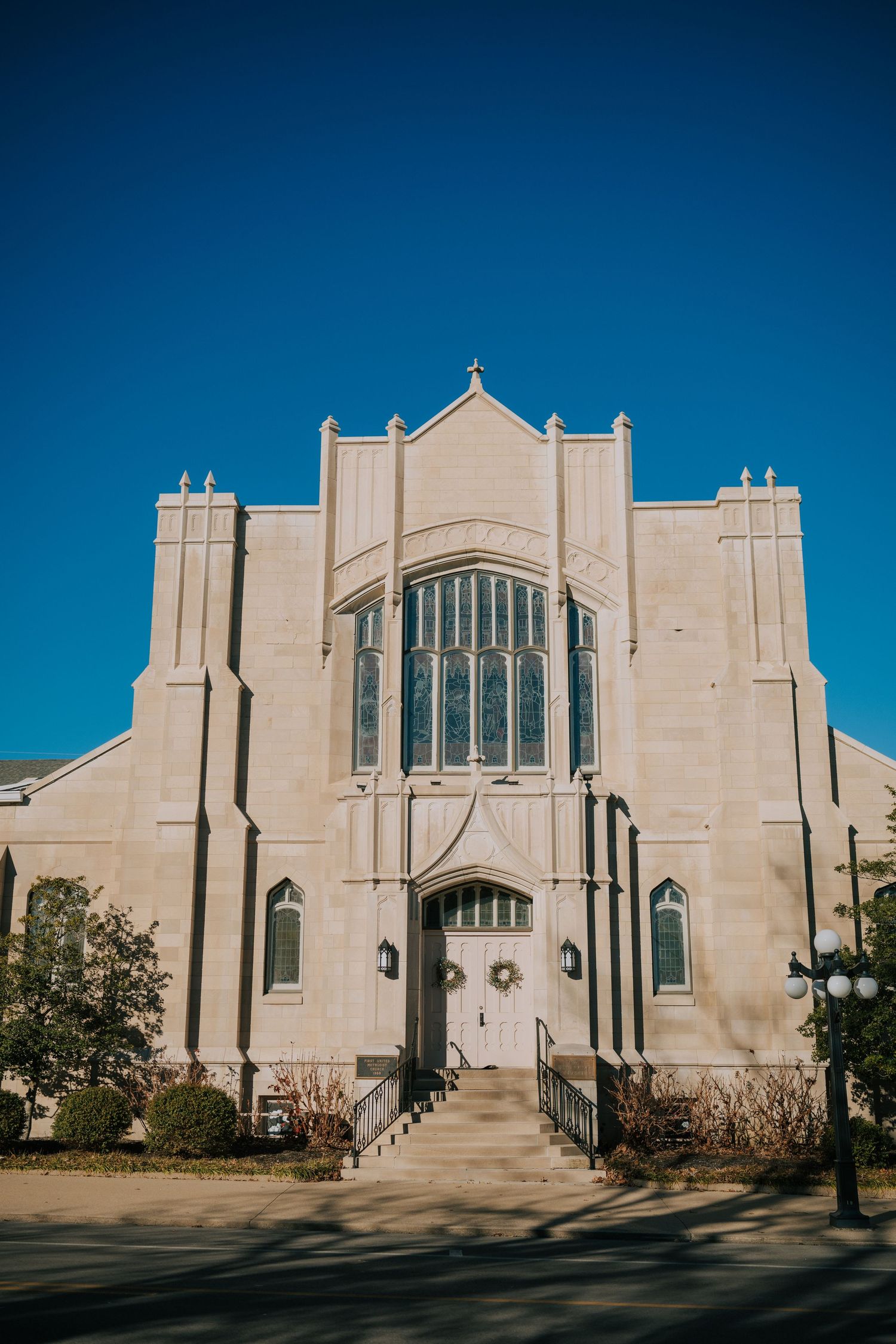 Exterior view of a grand Gothic-style church with cream colored stone and large windows against a blue sky.