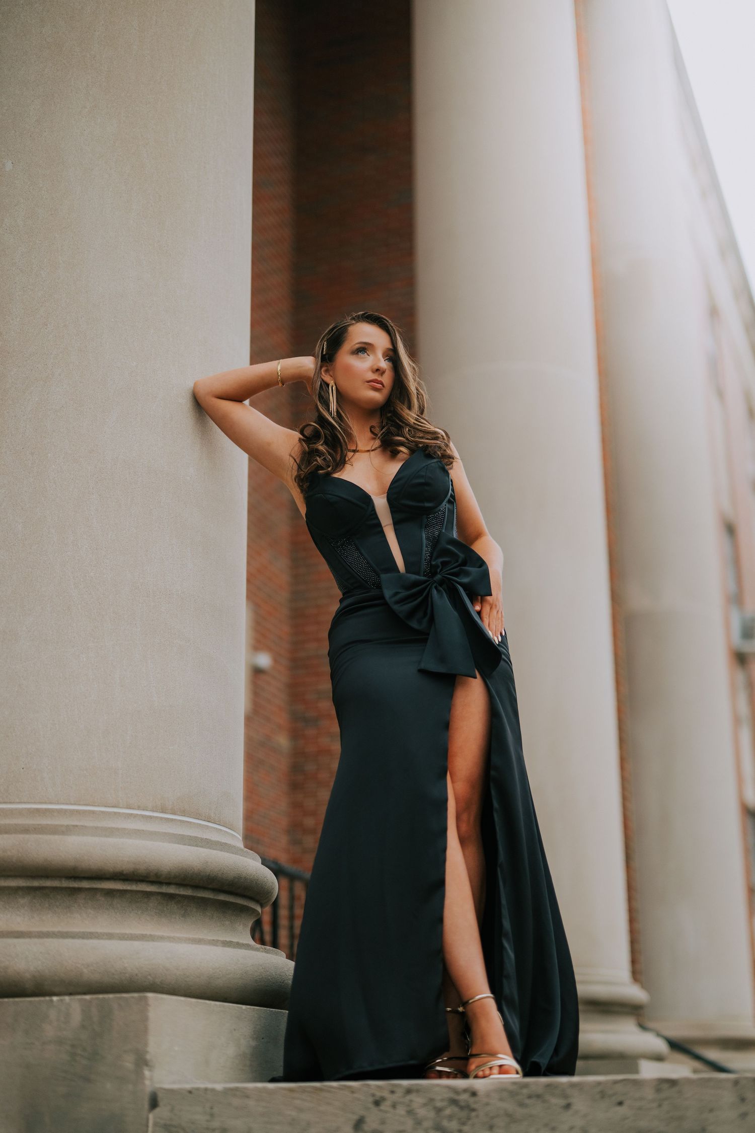 Dramatic portrait between white columns featuring elegant black dress and architectural elements.