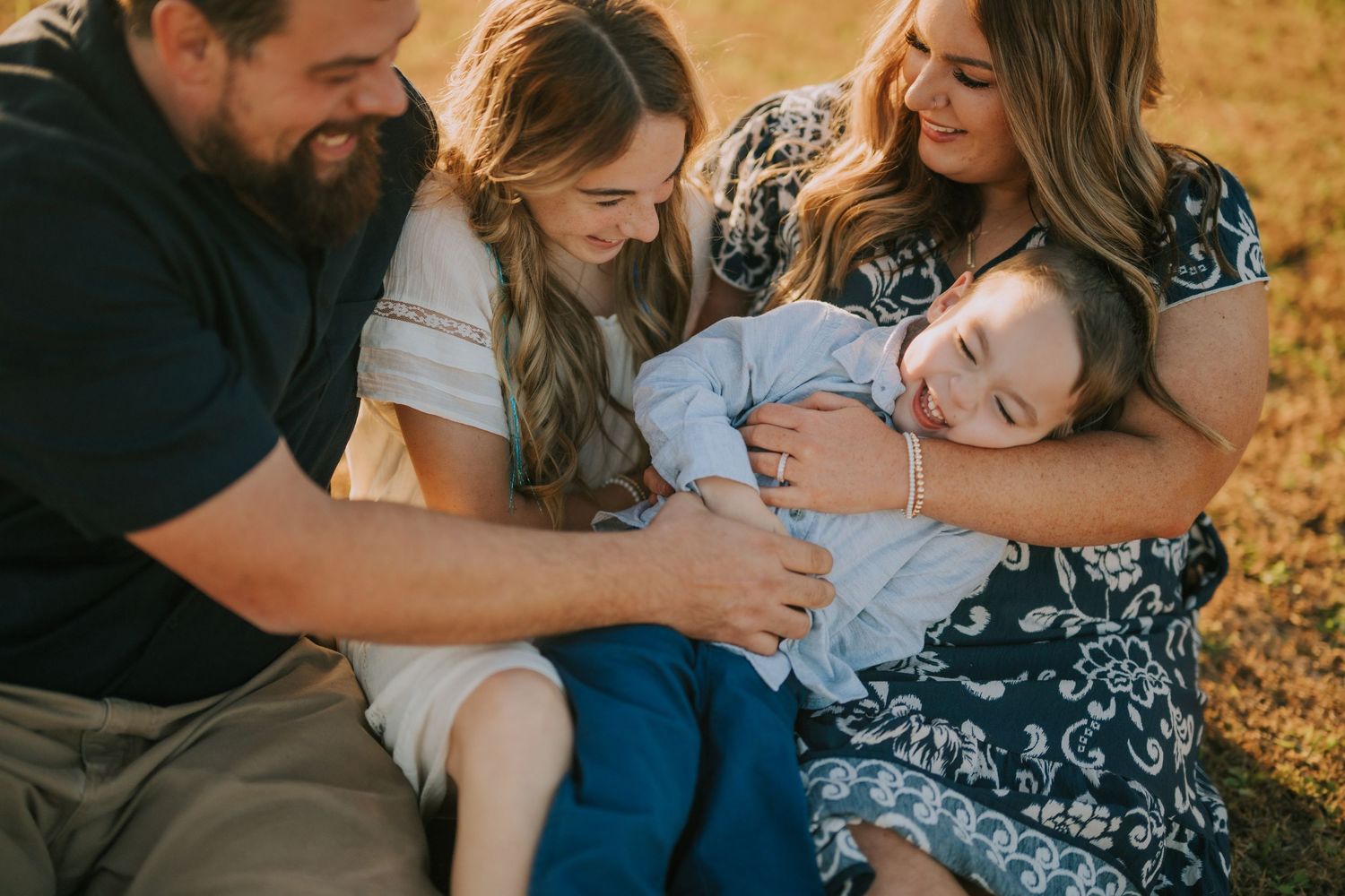 Candid family moments captured in a sun-drenched field during golden hour.