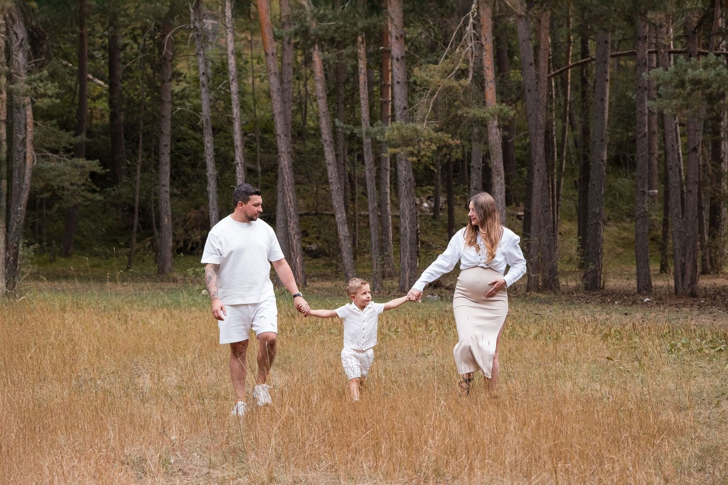 Family walking together through a scenic forest path in white clothing.
