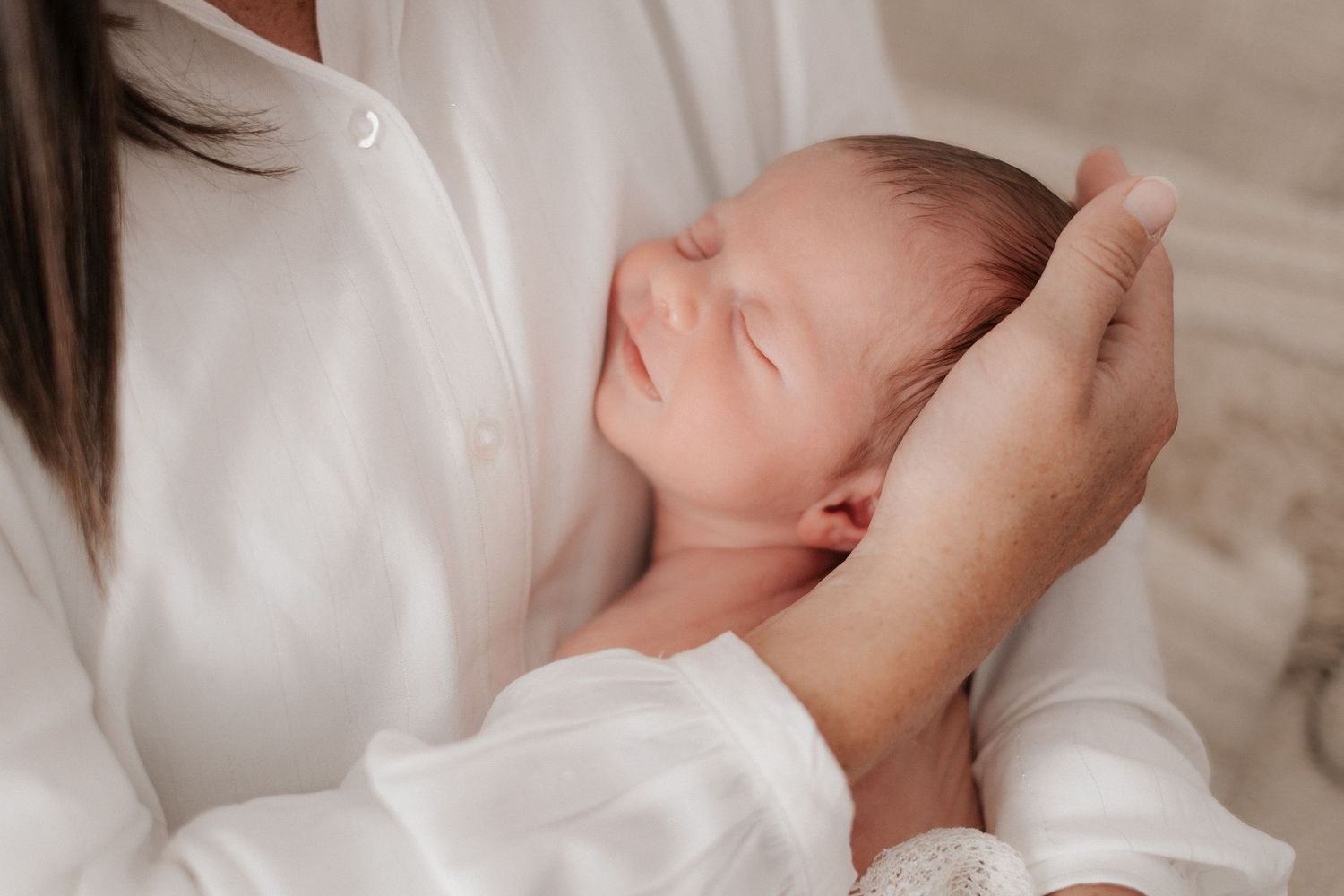 Mother holding and kissing baby in series of intimate portraits.