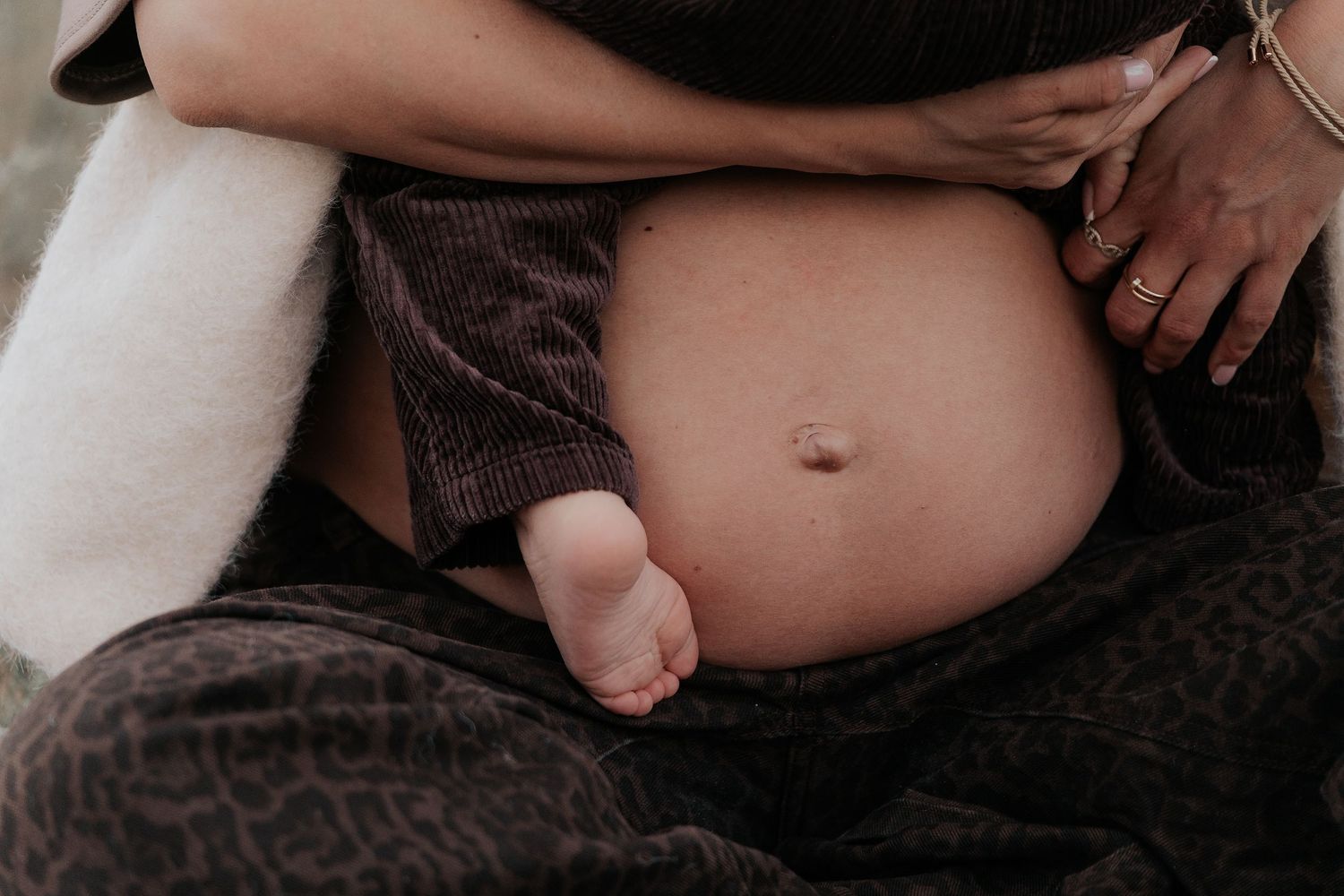 A black and white close-up photo of a newborn baby's tiny feet against a dark background.