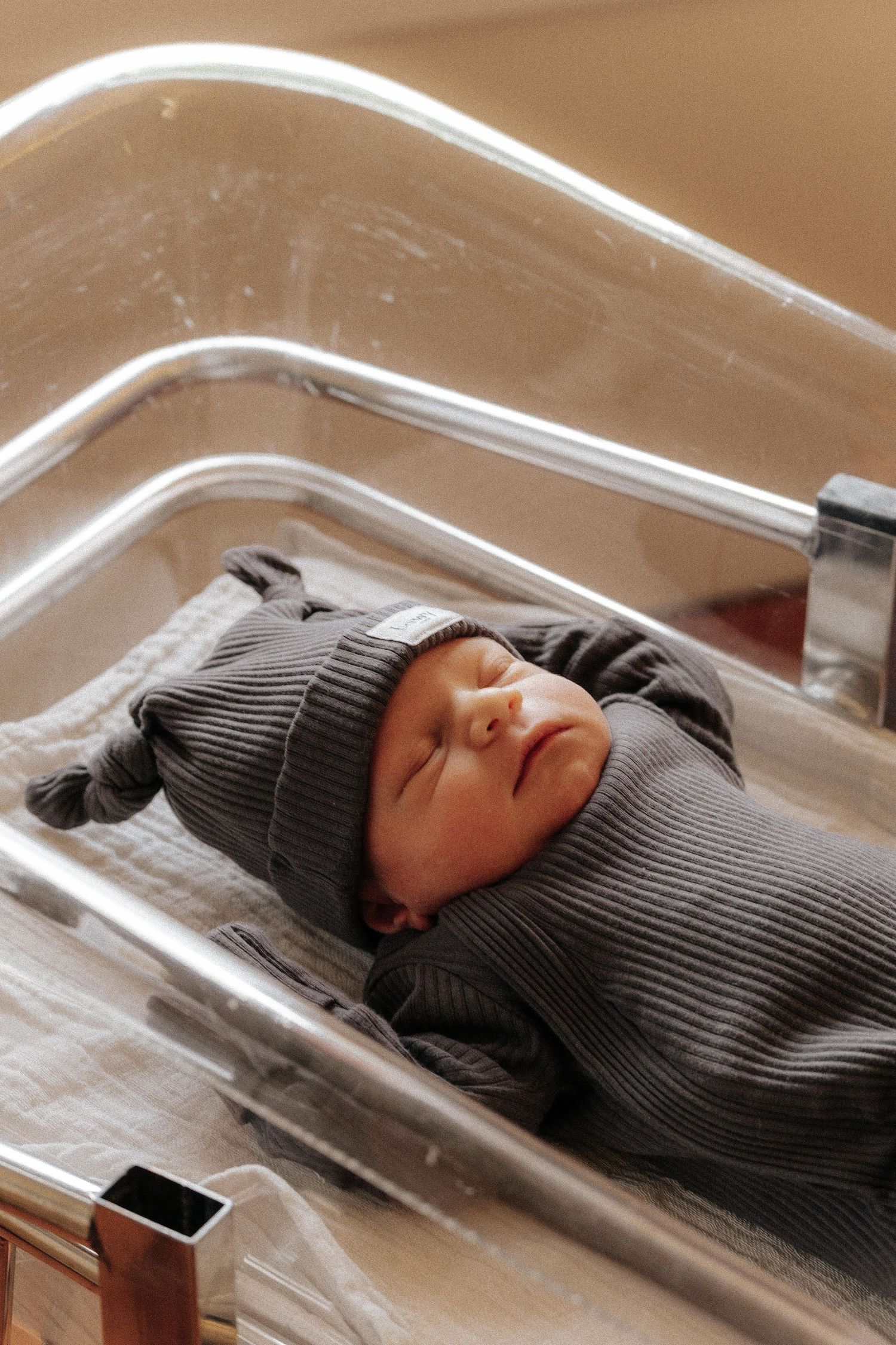 A person wearing a gray knit sweater lies asleep on a clear plastic surface.