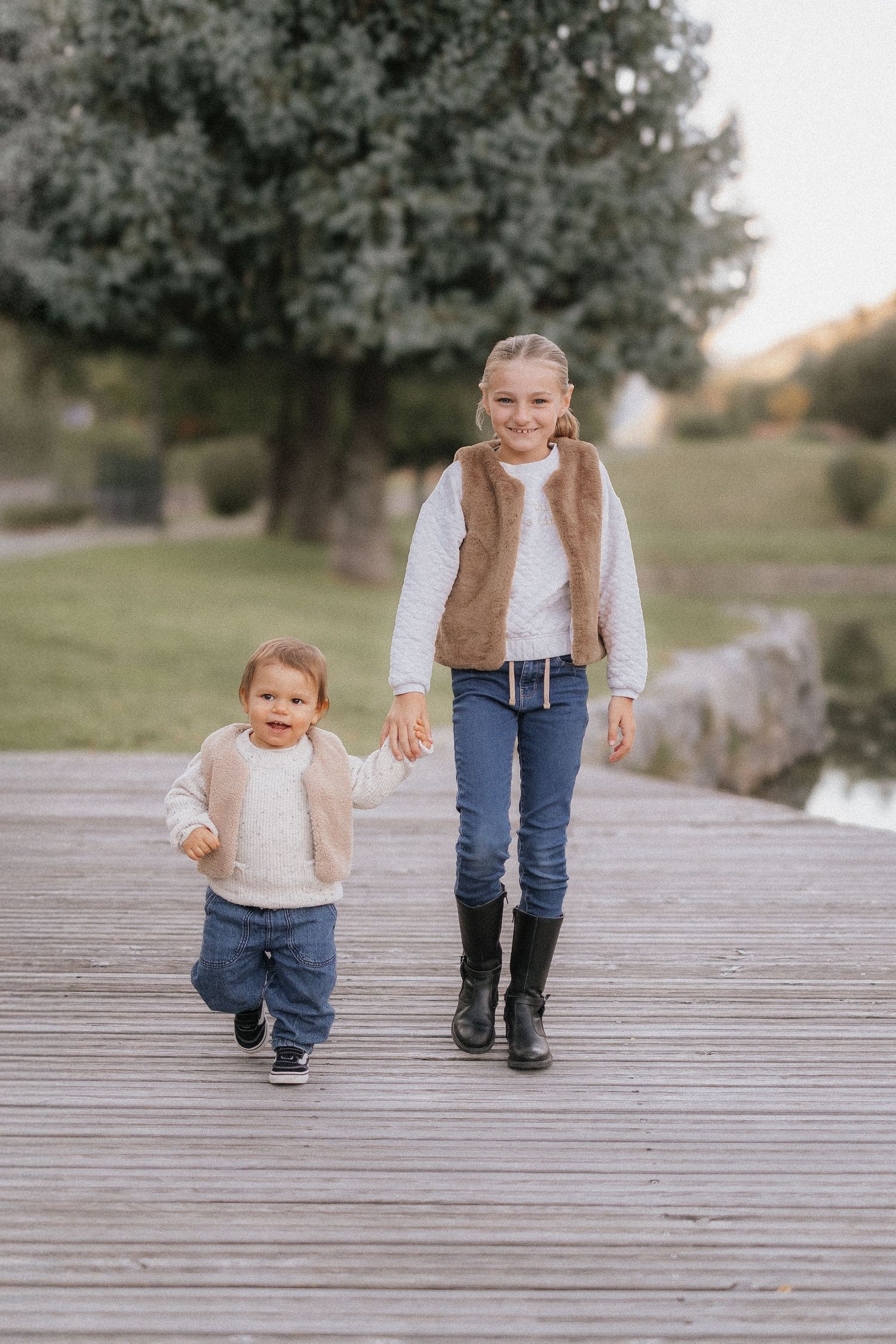 A sequence of photos showing a small child walking with an adult on a wooden boardwalk in a park setting.